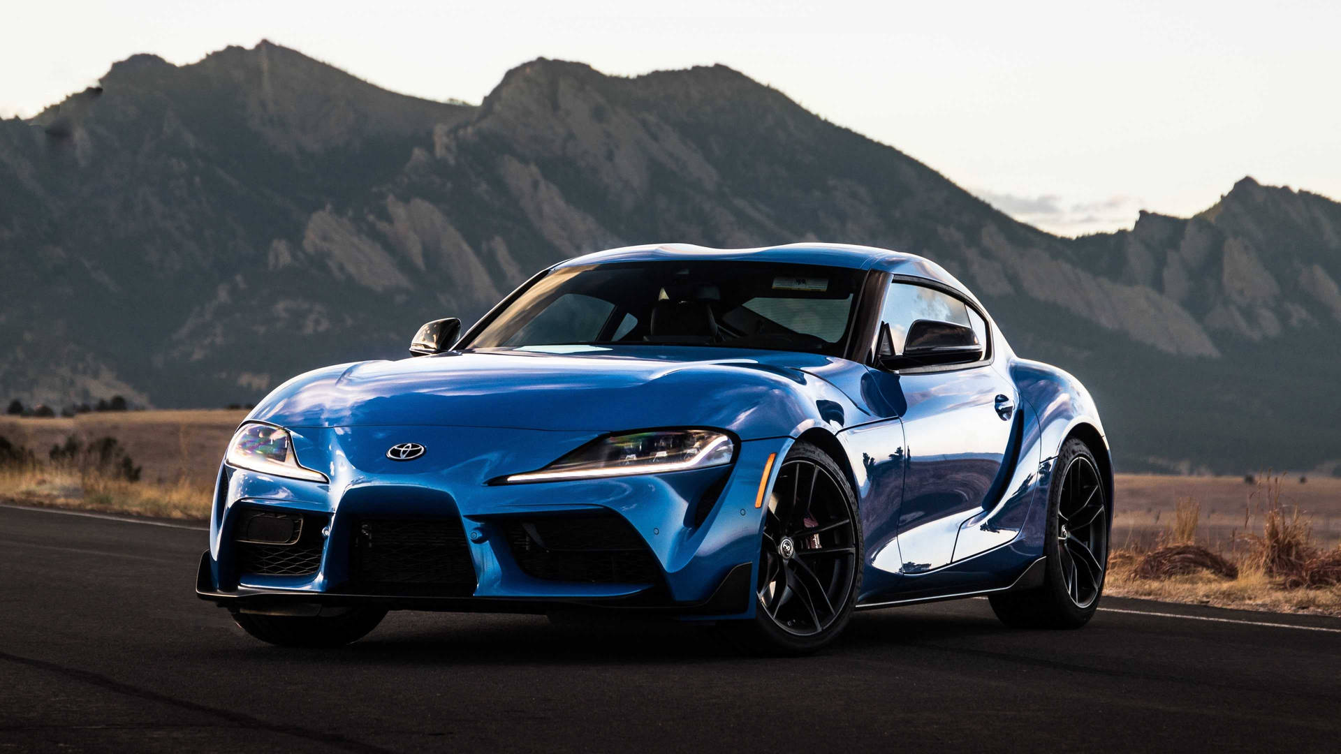 日落時分山路上的藍色跑車 — Toyota Supra 壁紙
