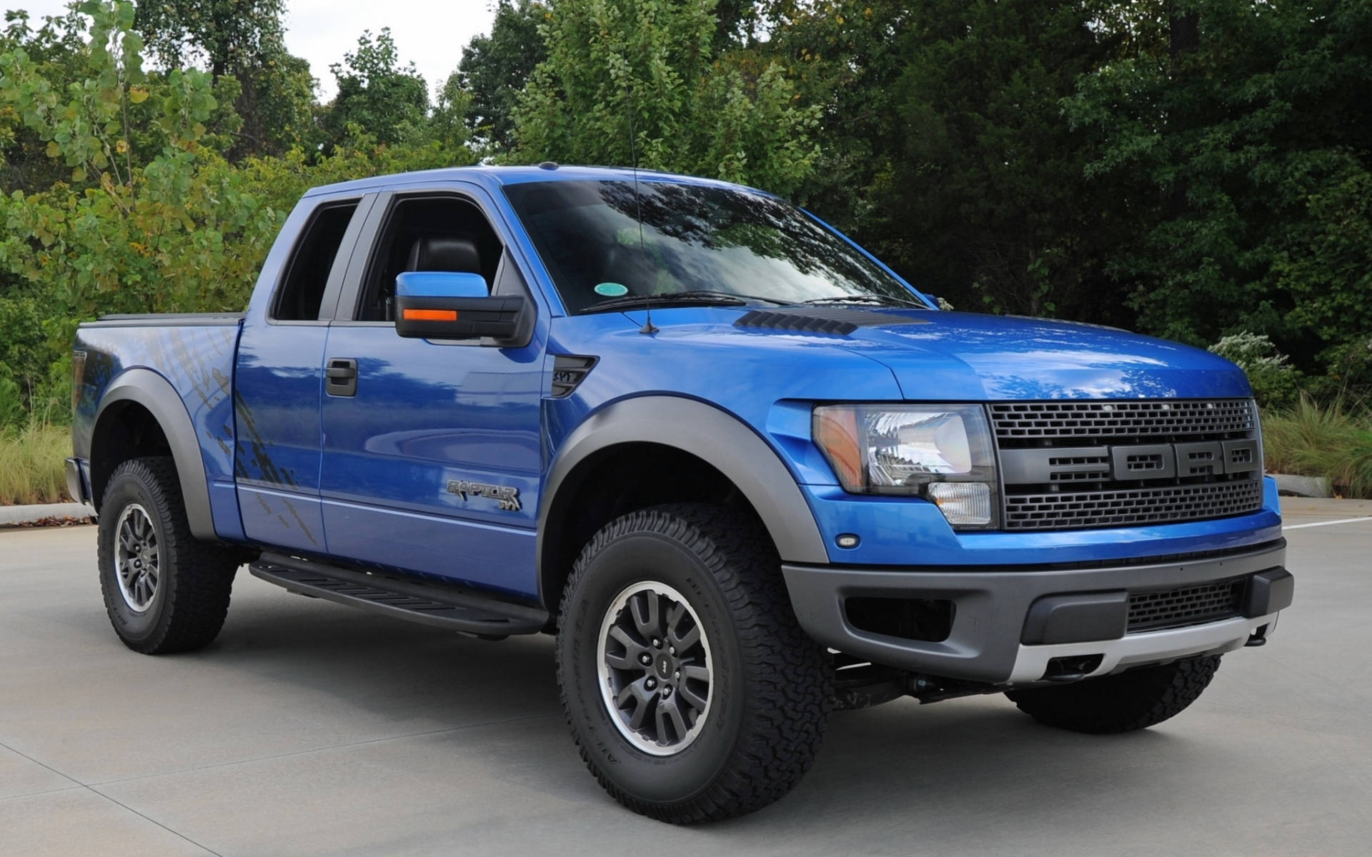 藍色福特 F-150 Raptor 皮卡車停在戶外樹木附近。 — 福特猛禽 壁紙