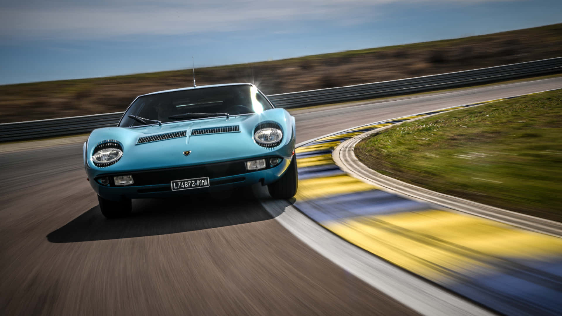 Lamborghini Miura 桌布 壁紙 — 一輛充滿活力的藍色經典跑車在賽道彎道上疾馳，動態模糊凸顯其速度。