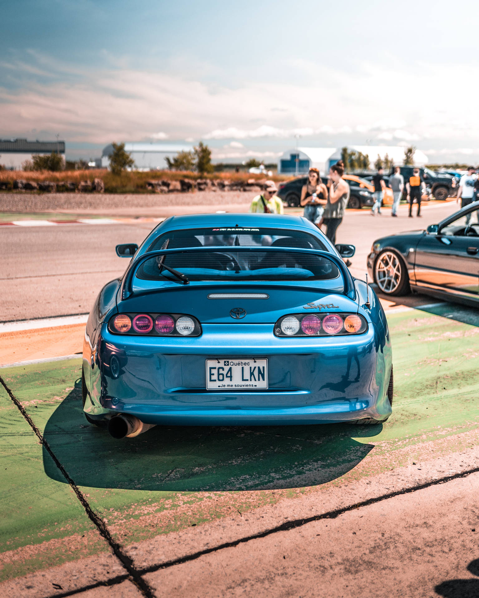 藍色跑車停在賽道上，附近有人。 — Toyota Supra 壁紙