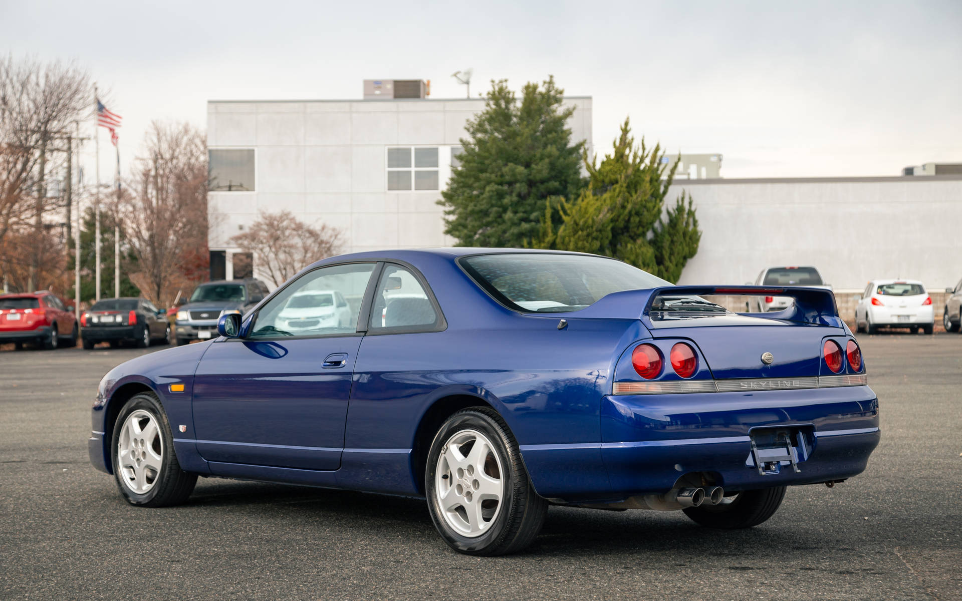藍色日產Skyline GT-R停泊在停車場，有樹木和建築物。 — 城市天際線汽車 壁紙