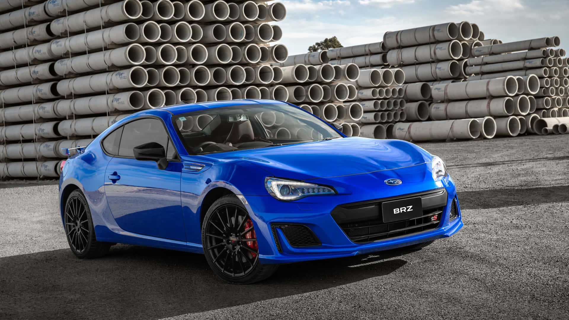 藍色Subaru BRZ跑車停在工業管道堆附近。 — Toyota Supra 壁紙