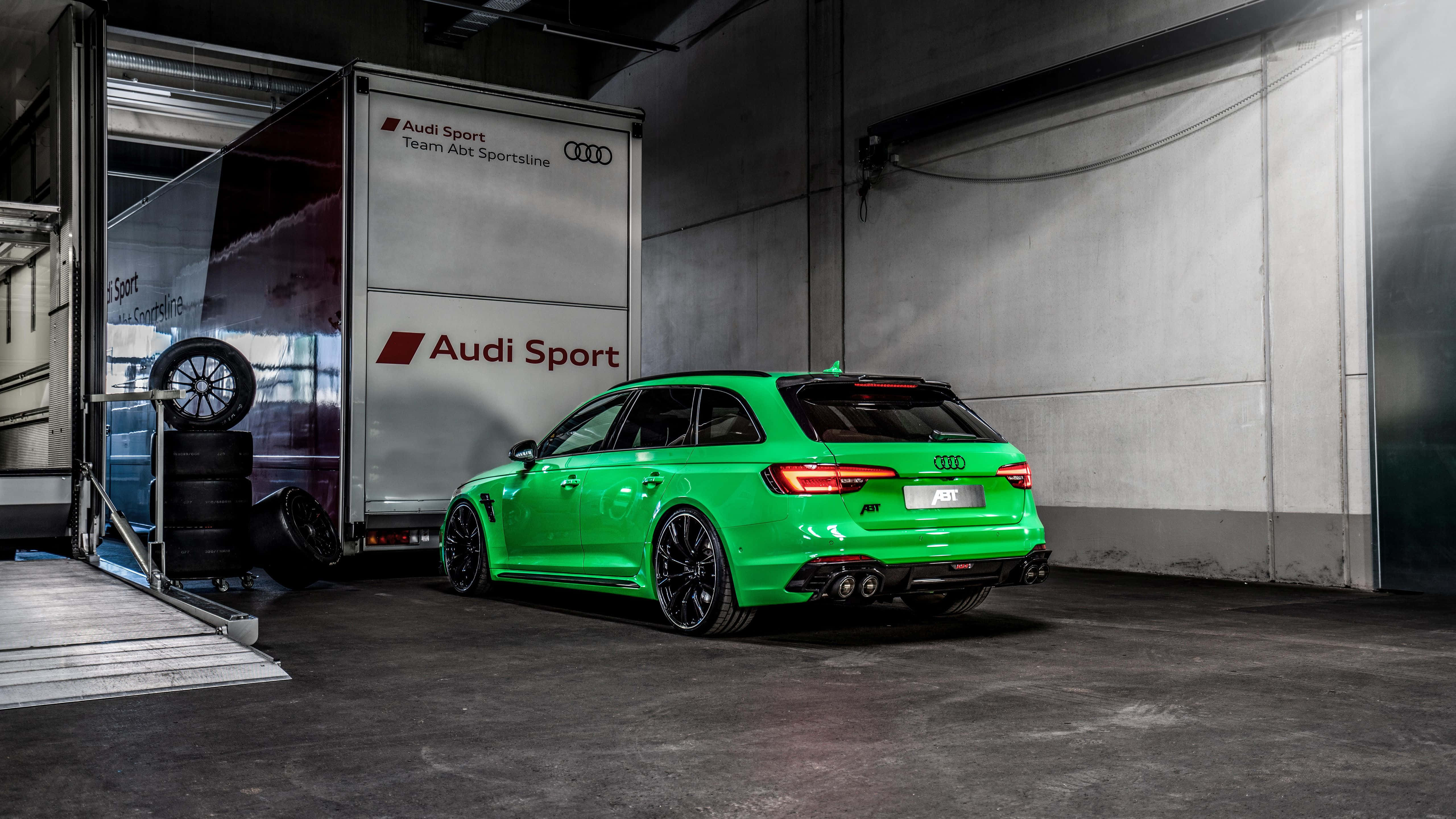 Audi Rs4 桌布 壁紙 — 一輛充滿活力的綠色Audi RS4 Avant高性能旅行車停放在混凝土車庫中，旁邊是Audi Sport拖車。