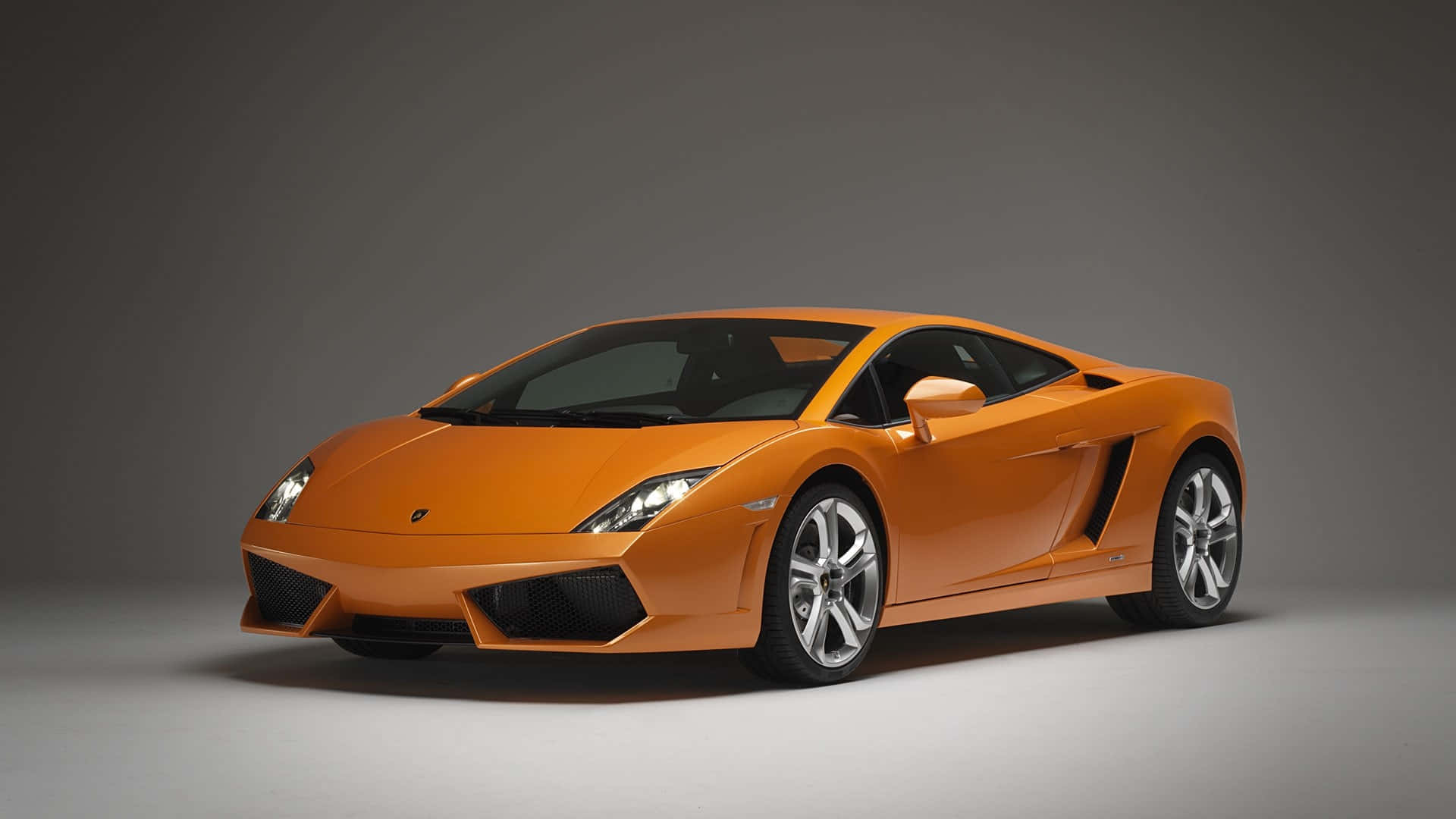 Lamborghini Gallardo 桌布 壁紙 — 一輛充滿活力的橙色藍寶堅尼Gallardo跑車以四分之三角度擺放在中性灰色工作室背景前。