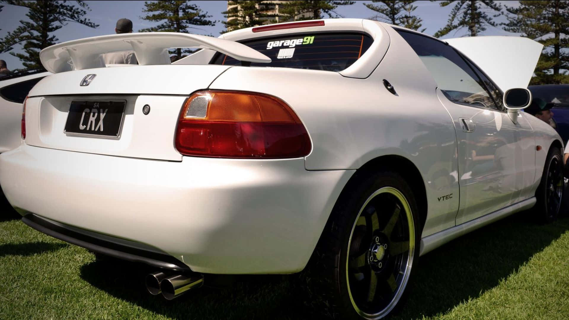 Honda Civic Del Sol 桌布 壁紙 — 一輛純白色的本田CRX跑車，引擎蓋打開，停放在明亮的日光下的綠色草地上。