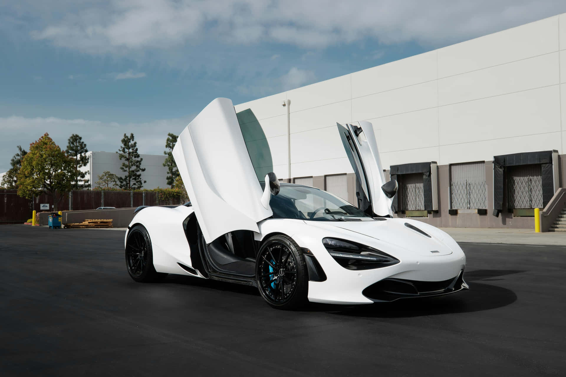  壁紙 — 一輛純白色的McLaren跑車，鷗翼車門打開，停在部分多雲的天空下的瀝青地上。