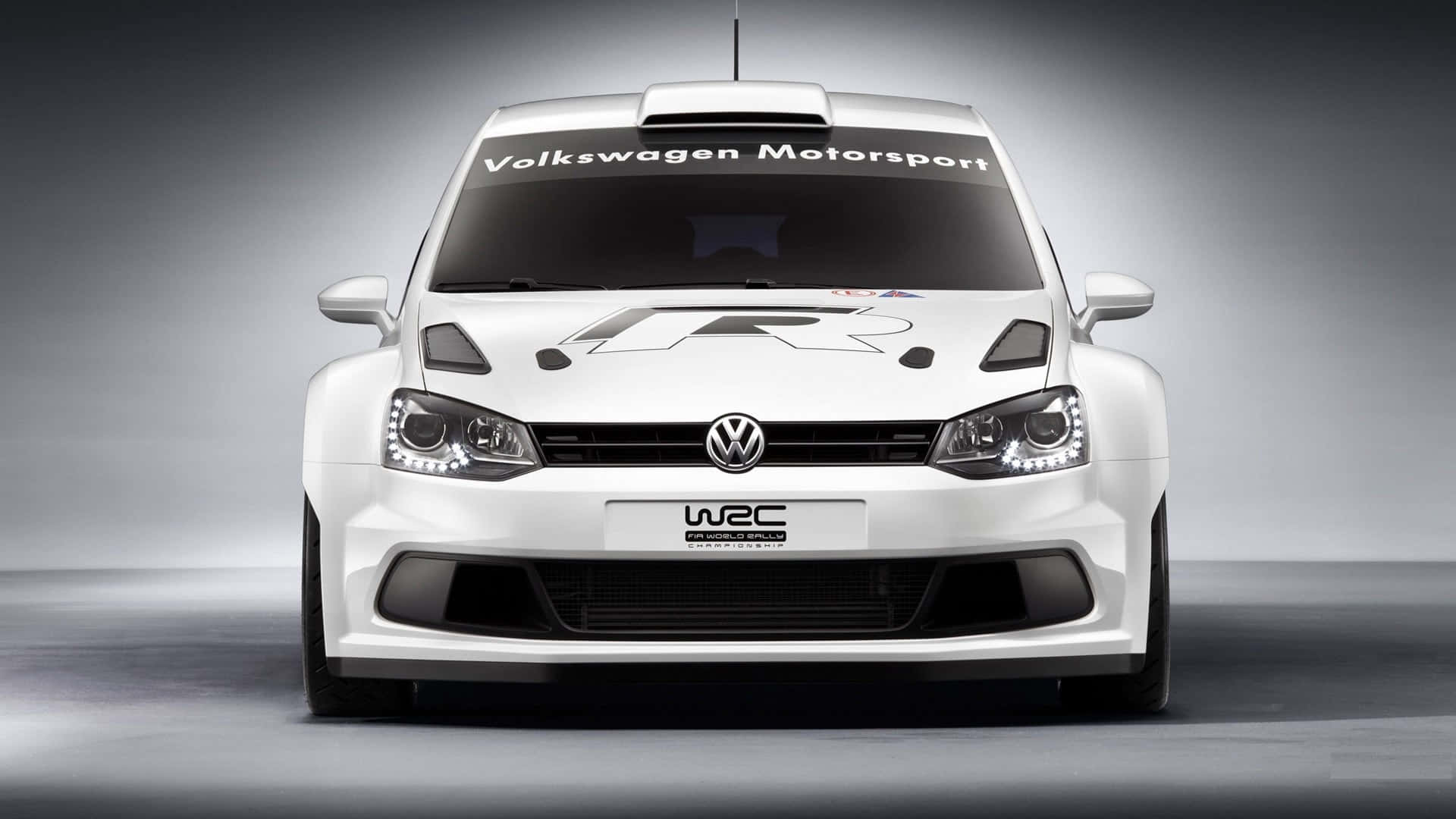Volkswagen Polo 桌布 壁紙 — 一輛純白色福斯汽車拉力賽車在攝影棚內正面朝前，搭配戲劇性燈光和漸變灰色背景。