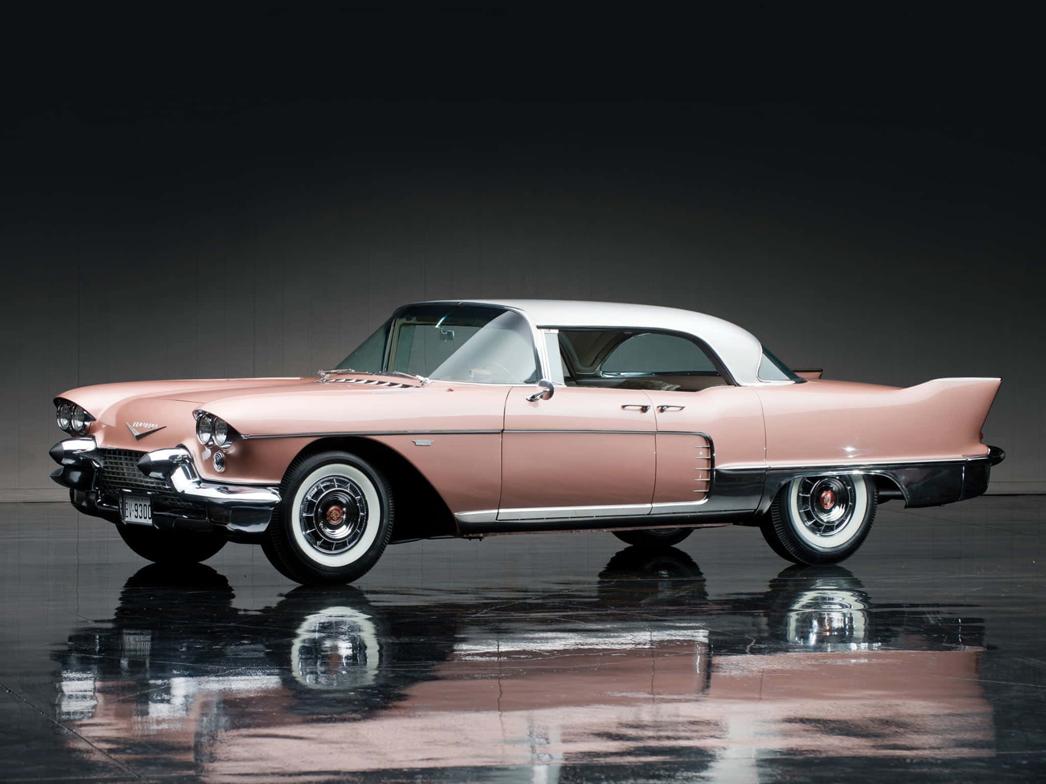 Cadillac Eldorado 桌布 壁紙 — 一輛帶有鍍鉻細節的復古粉白凱迪拉克在黑色光澤地板上反射，背景為深色攝影棚。