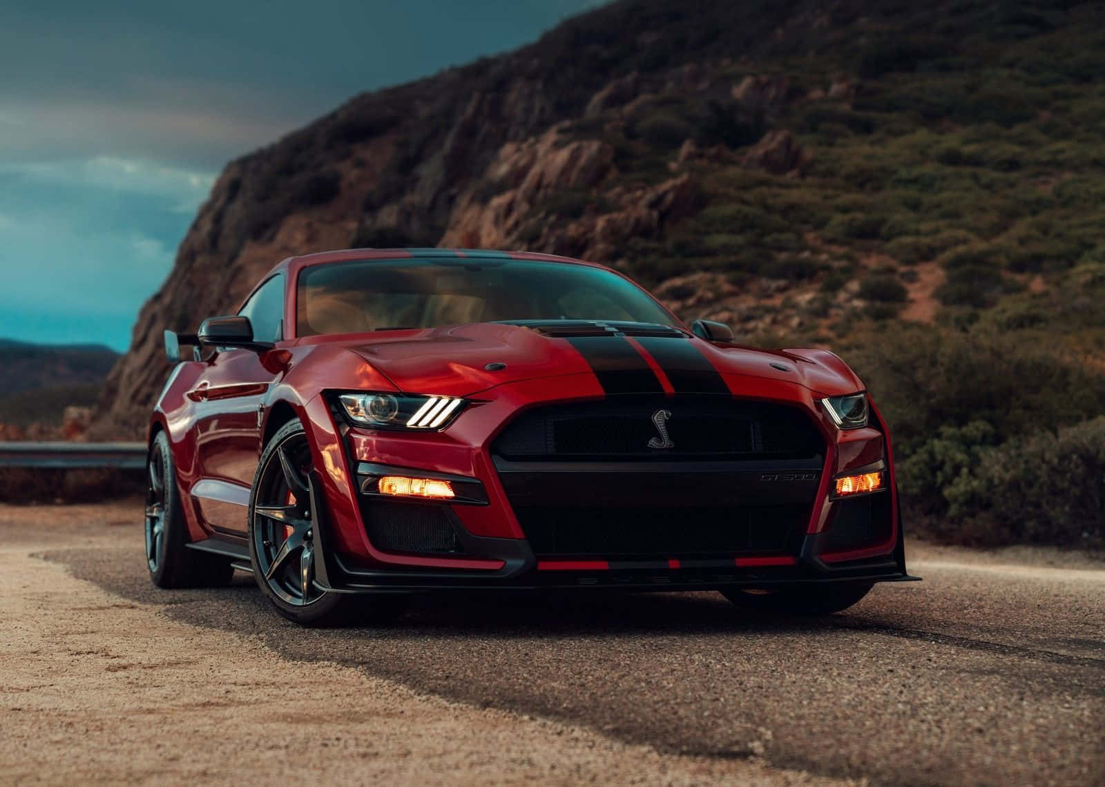  壁紙 — 一輛帶有黑色賽車條紋的紅色福特野馬Shelby GT500，在黃昏時停在山路上。