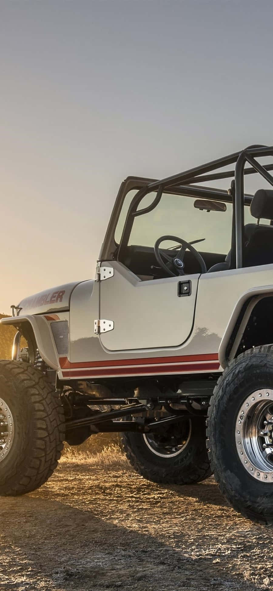 Jeep Cj 桌布 壁紙 — 一輛帶有紅色條紋的銀色越野Jeep Wrangler在黃金時段停泊在岩石地形上。