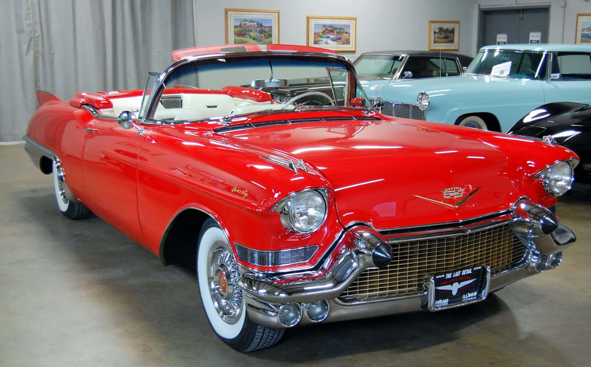 Cadillac Eldorado 桌布 壁紙 — 一輛光澤的紅色1959年凱迪拉克敞篷車，帶有鍍鉻細節和白色輪胎，在明亮的室內燈光下閃閃發光。