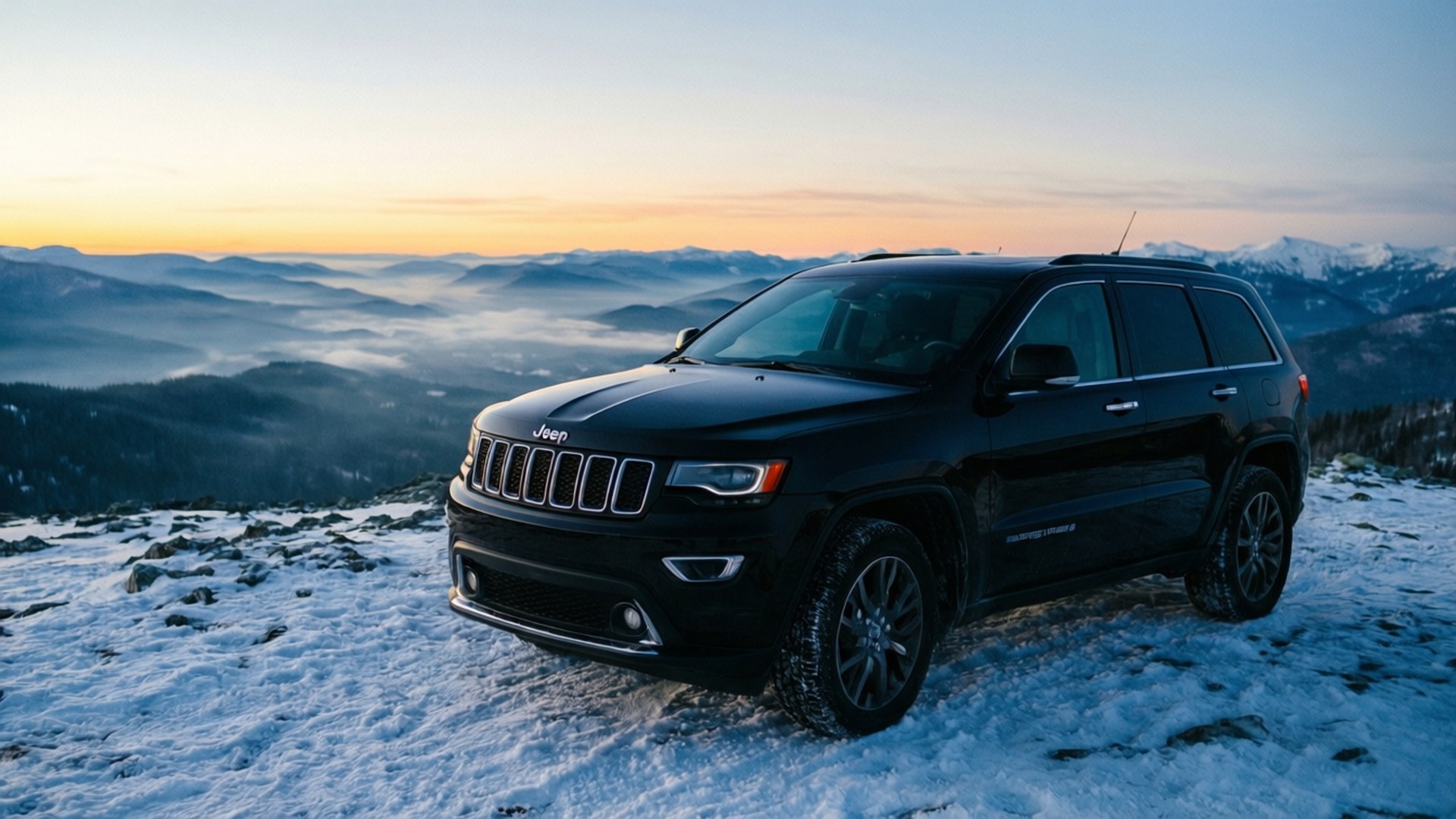 Summit at Dawn 壁紙 — 一輛黑色Jeep Grand Cherokee停在白雪覆蓋的山脊上，俯瞰日出時霧氣瀰漫的山谷。