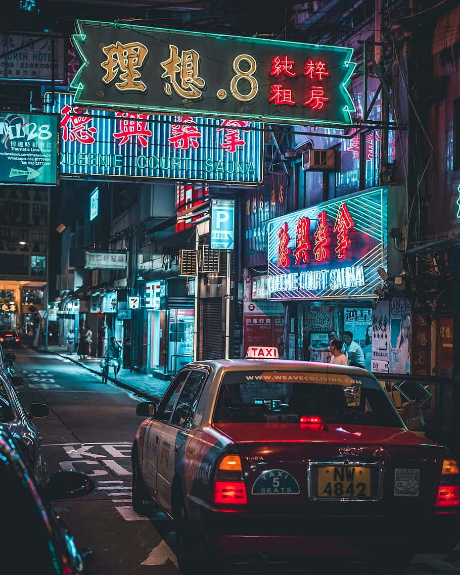  壁紙 — 一輛紅色計程車停在繁華亞洲城市小巷中閃爍的霓虹燈招牌下。