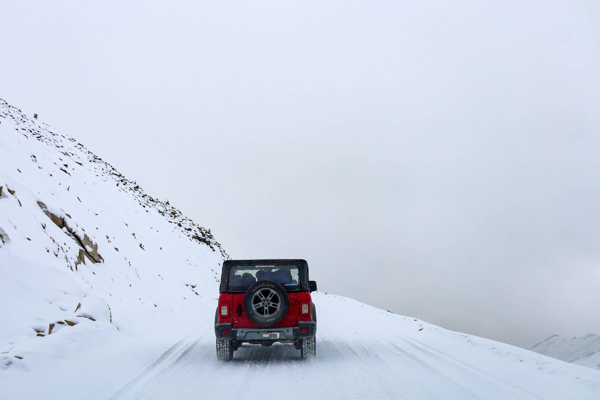 紅色吉普車在冬季積雪的山路上行駛。 — 汽車 4K 壁紙