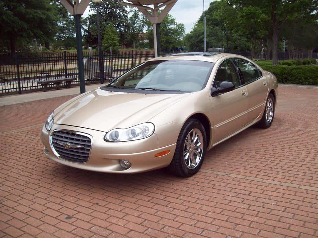 Chrysler Lhs 桌布 壁紙 — 一輛金色克萊斯勒轎車停放在紅磚庭院上，上方有遮蓋的涼亭，背景有綠樹。