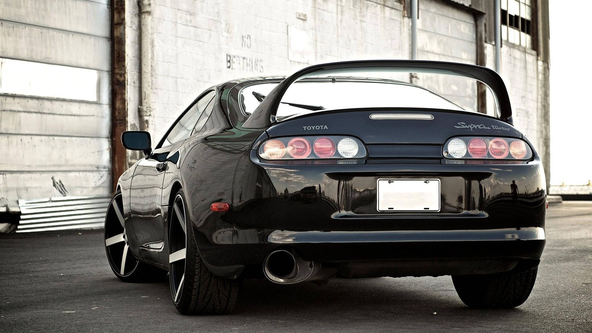 黑色豐田Supra跑車停放在工業建築前。 — Toyota Supra 壁紙