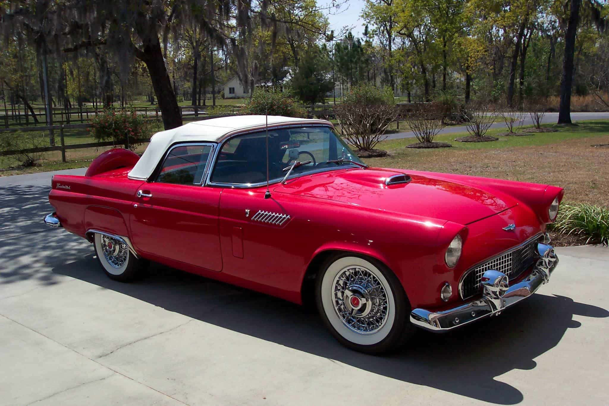Ford Thunderbird 桌布 壁紙 — 一輛亮麗的紅色1955年福特雷鳥敞篷車，白色車頂，停在陽光明媚的混凝土車道上。