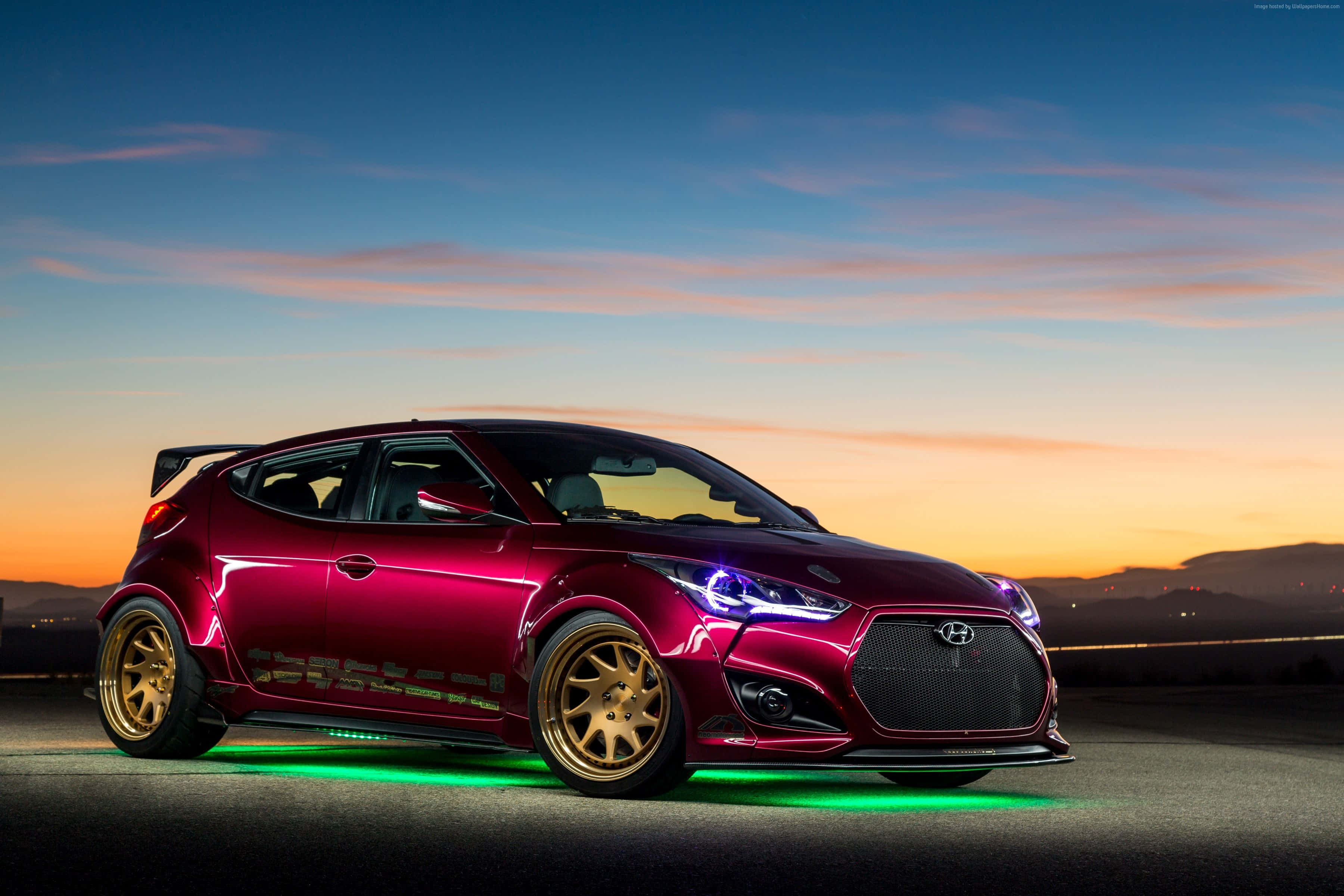 Hyundai Veloster 桌布 壁紙 — 一輛亮面栗色改裝現代Veloster，配金色輪圈和發光綠色底盤燈，停在日落時分的道路上。