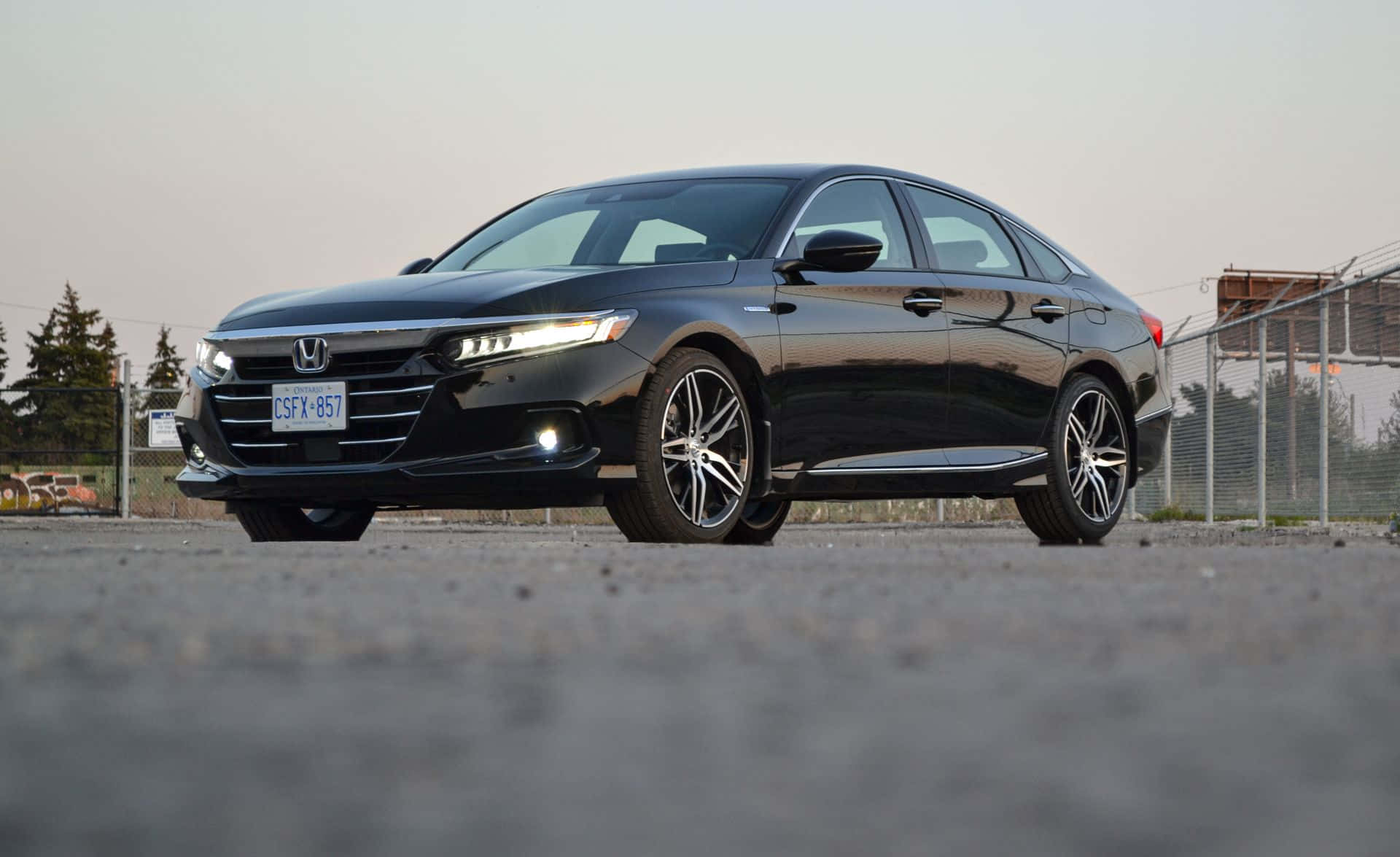 Honda Accord 桌布 壁紙 — 一輛流線型黑色本田雅閣轎車在柔和日光下停在碎石上，靠近鐵絲網圍欄，閃閃發光。