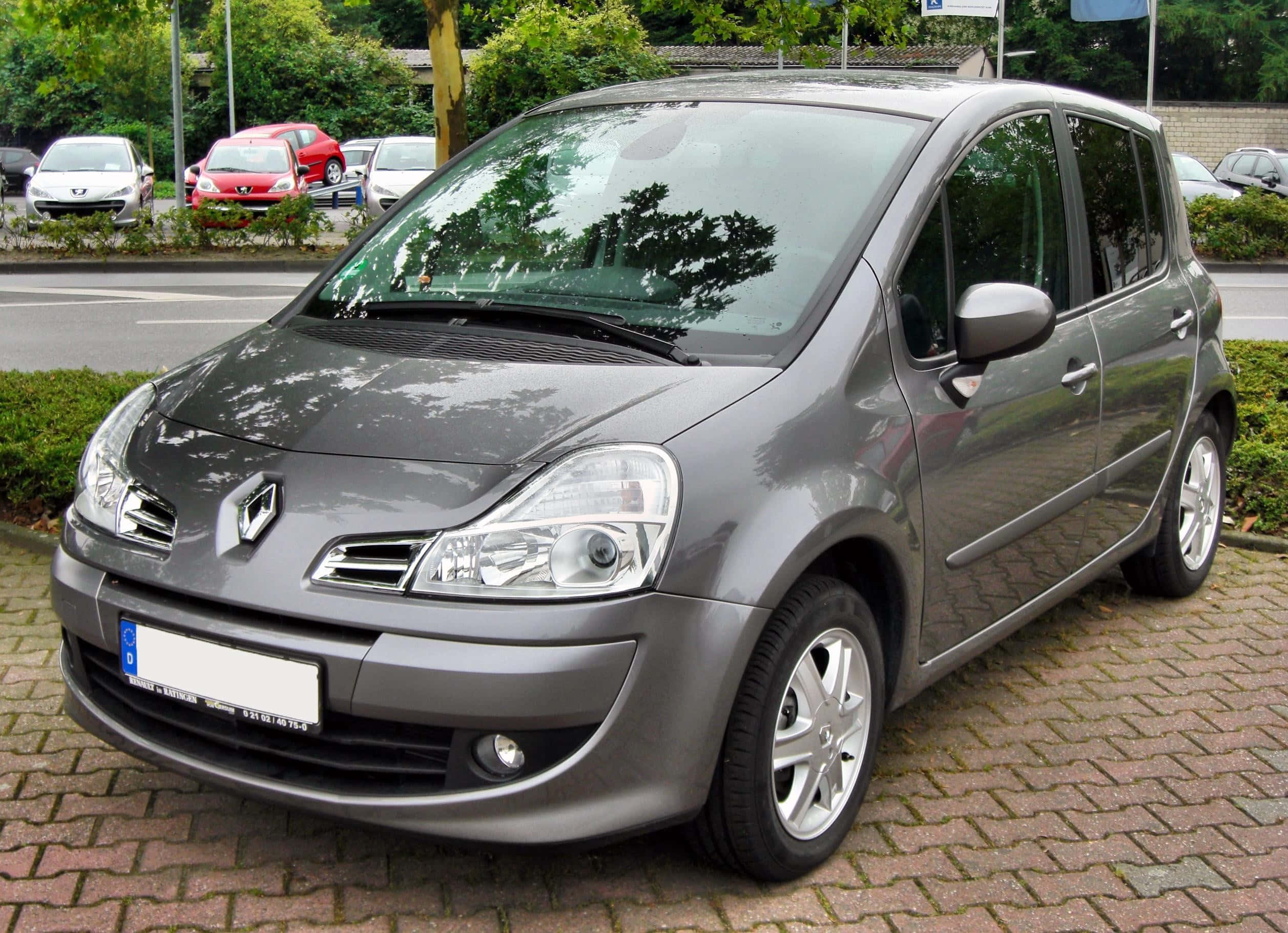 Renault Modus 桌布 壁紙 — 一輛流線型灰色雷諾Scenic停放在磚砌停車場，背景有綠化及其他車輛。