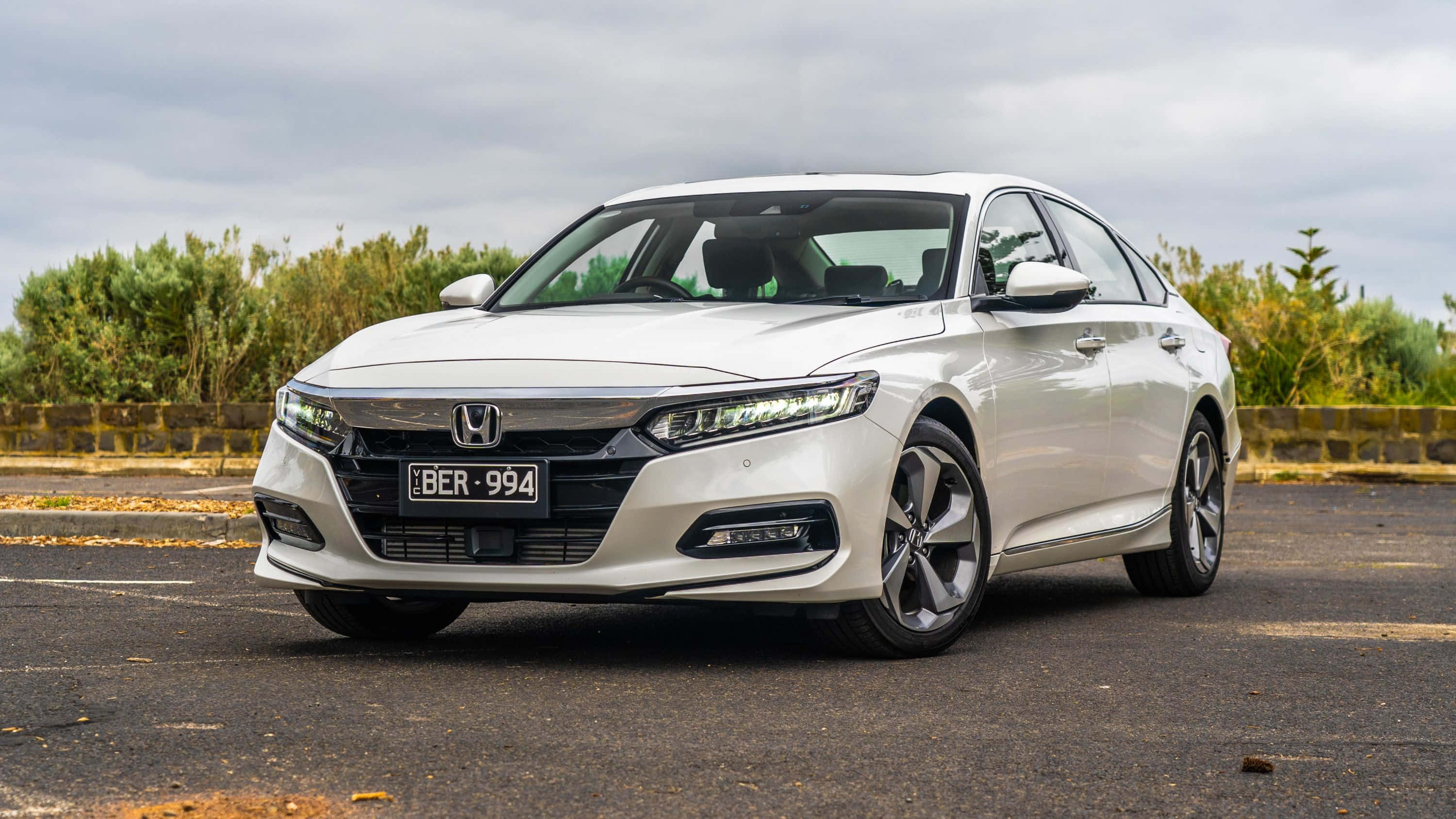 Honda Accord 桌布 壁紙 — 一輛時尚的白色本田雅閣轎車停在柏油路上，背景有綠色灌木叢和陰天。
