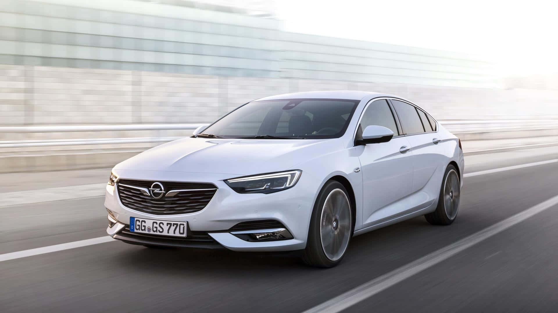 Opel Insignia 桌布 壁紙 — 一輛時尚的白色歐寶轎車在現代高速公路上疾馳，動態模糊強調了其動態運動。