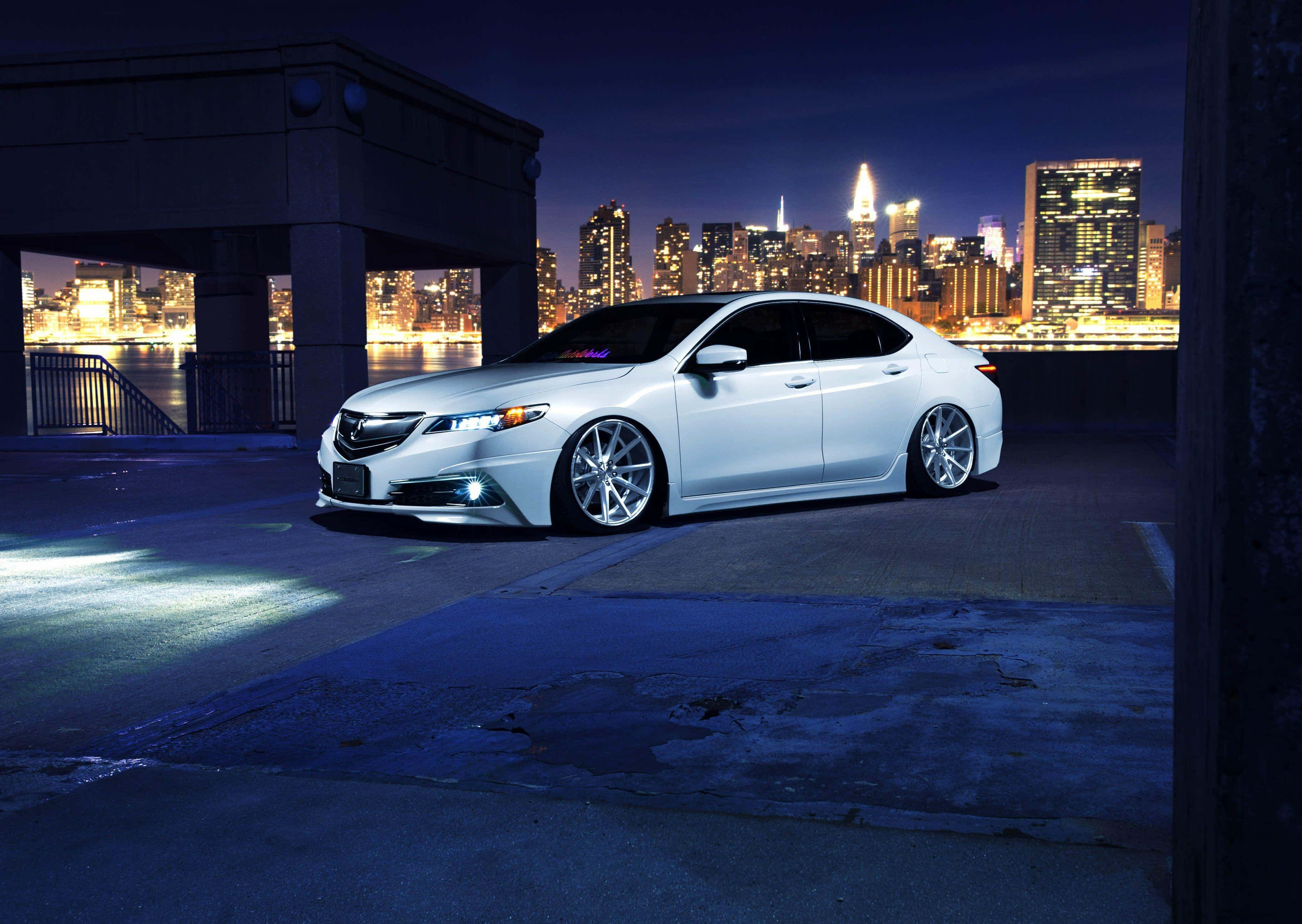 Acura Tlx 桌布 壁紙 — 一輛時尚的白色跑車在繁華的夜空下，於城市燈光中閃耀。