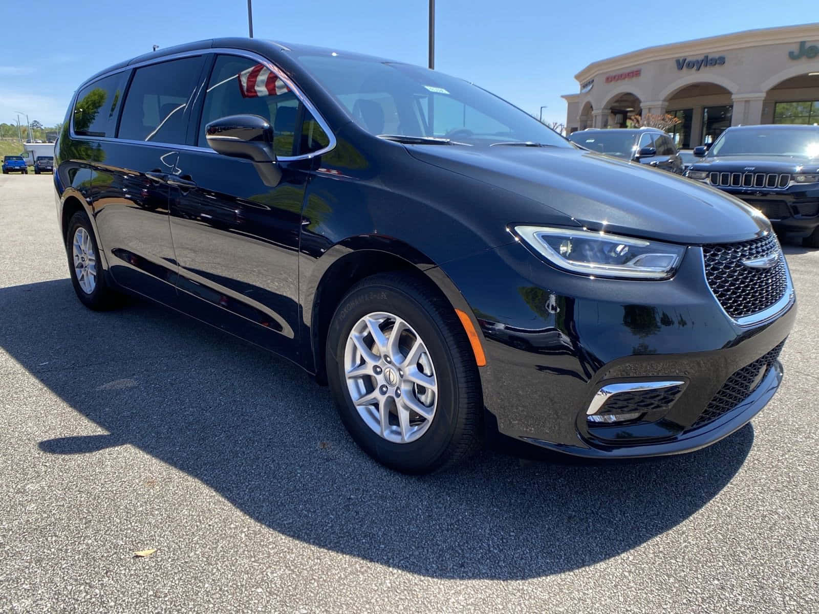 Chrysler Pacifica 桌布 壁紙 — 一輛時尚的黑色Chrysler Pacifica小型貨車在經銷商停車場的明亮陽光下閃閃發光。