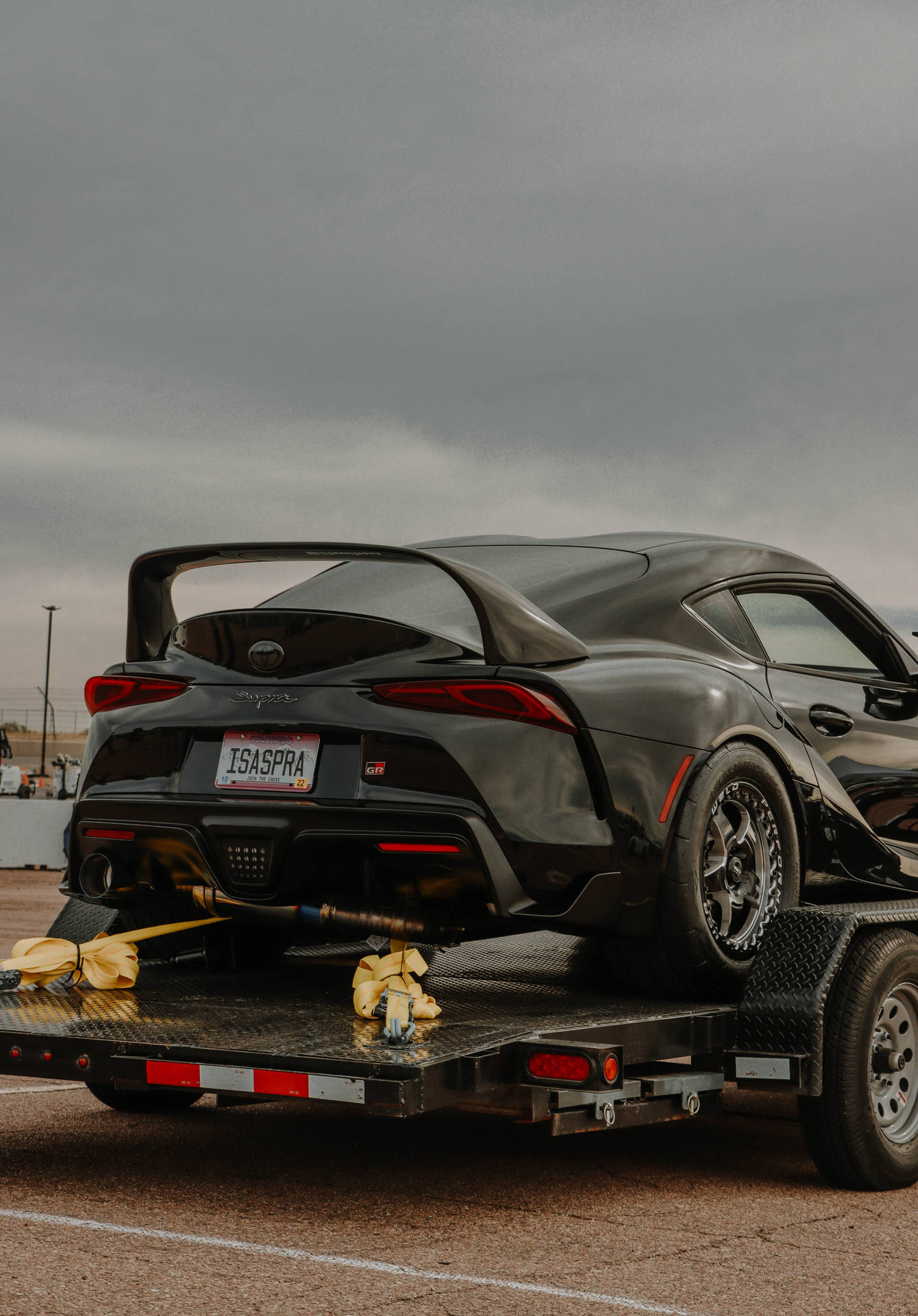 黑色豐田GR Supra在平板拖車上，天空多雲。 — Toyota Supra 壁紙