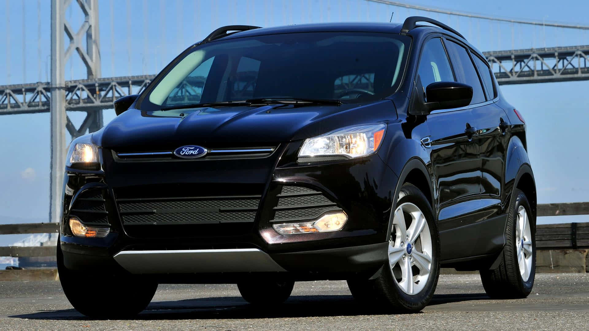 Ford Escape 桌布 壁紙 — 一輛時尚的黑色福特Escape SUV停在橋上，車頭燈亮著，背景是晴朗的藍天。