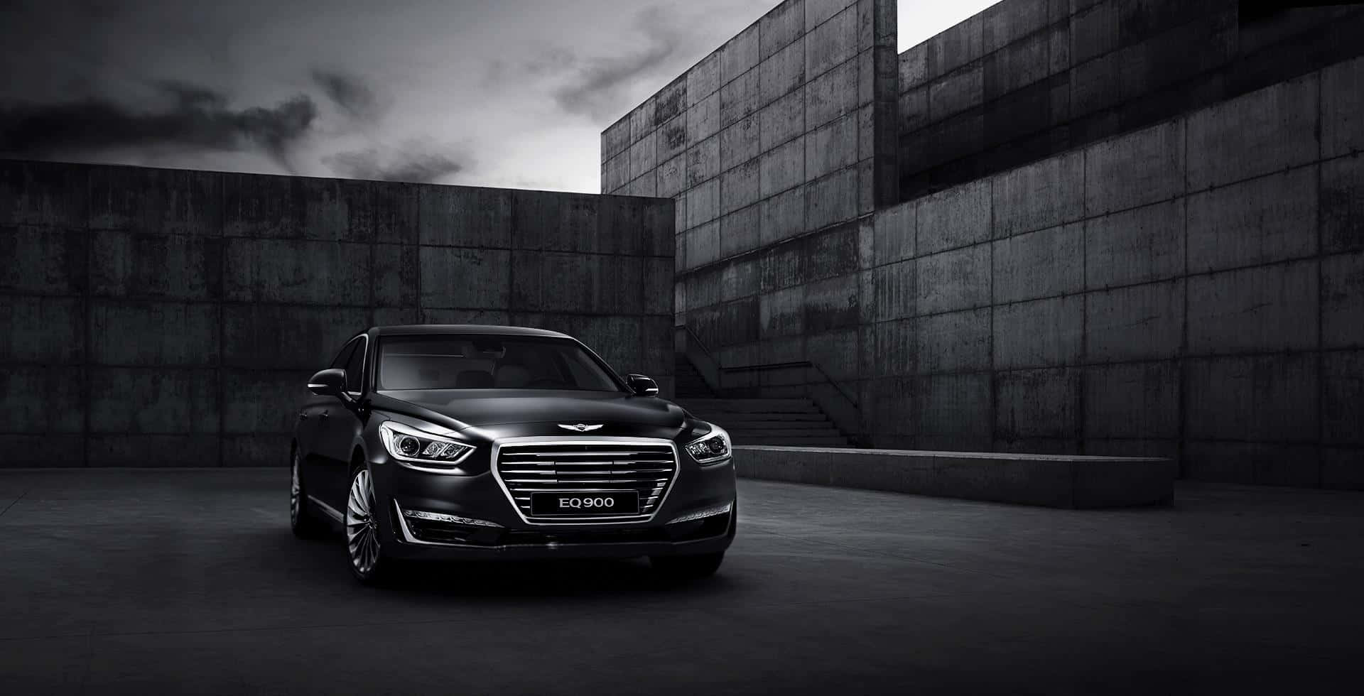 Genesis G80 桌布 壁紙 — 一輛時尚的黑色豪華轎車停放在簡樸的混凝土庭院中，天空陰沉多雲。