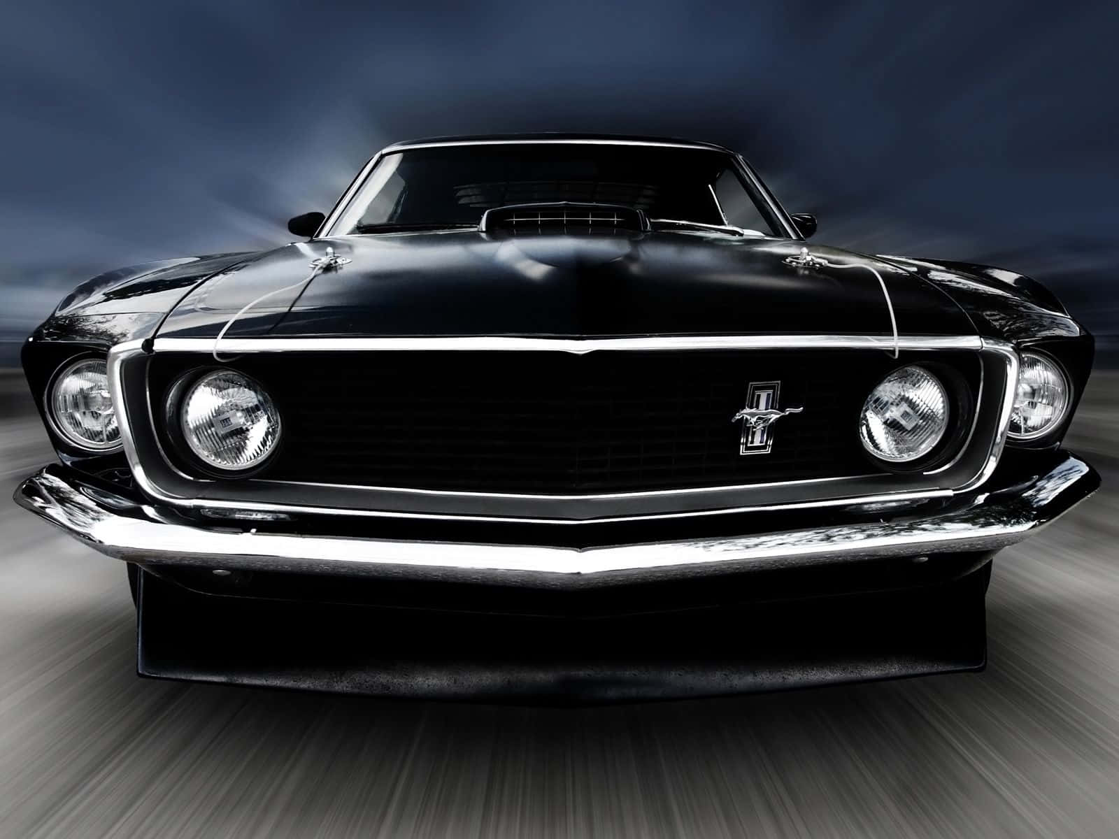 Ford Mustang Mach 1 桌布 壁紙 — 一輛時尚的黑色經典野馬在戲劇性的暴風雨天空下疾馳，鍍鉻飾邊閃閃發光。