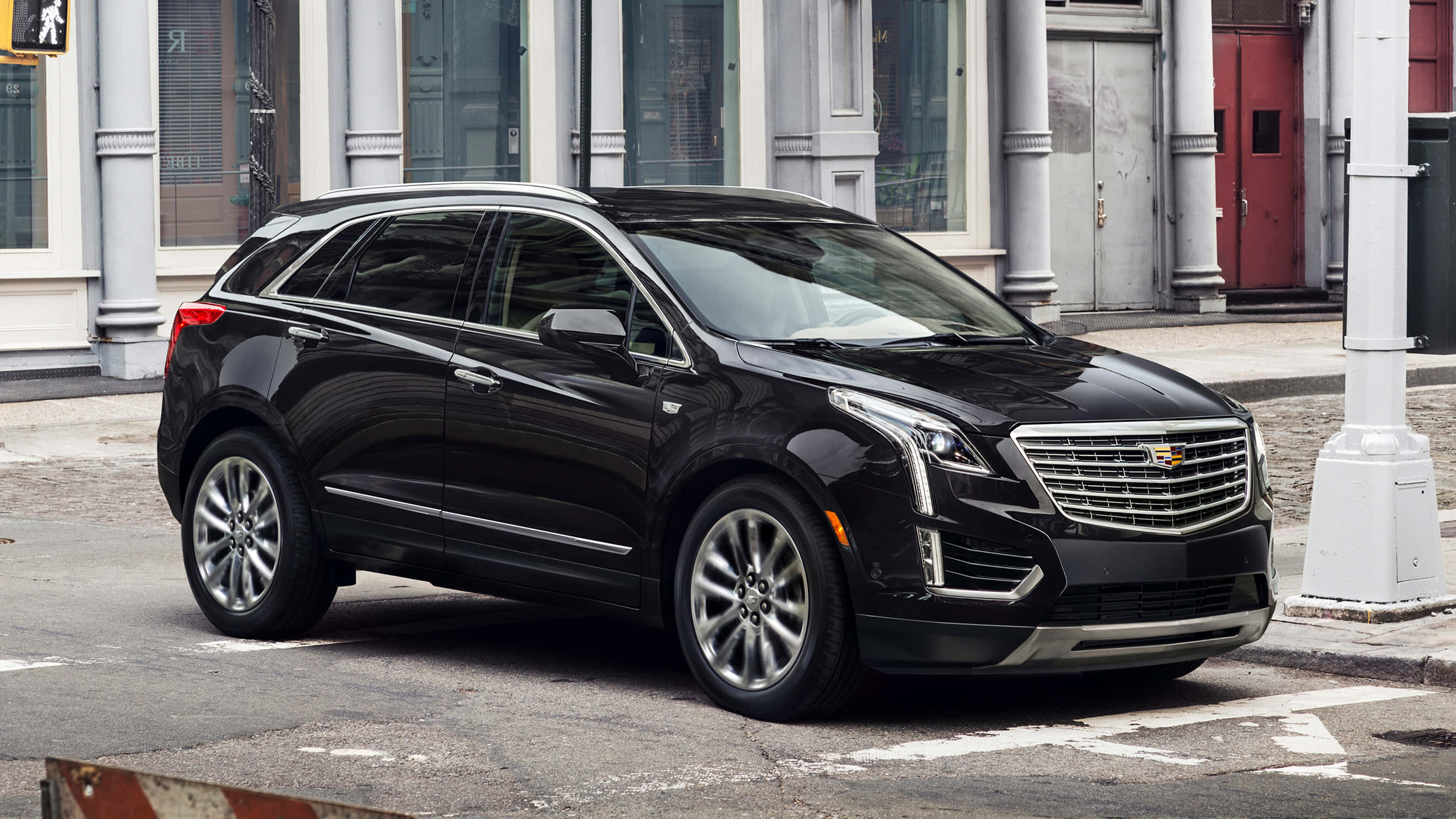 Cadillac Xt5 桌布 壁紙 — 一輛時尚的黑色凱迪拉克SUV停泊在城市的街道上，旁邊是一座有白色柱子和紅色門的建築物。