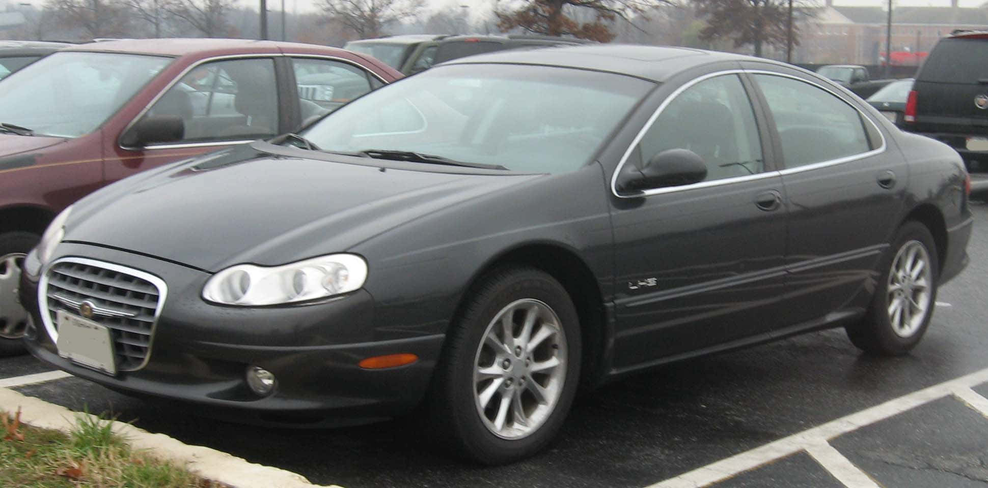 Chrysler Lhs 桌布 壁紙 — 一輛時尚的黑色克萊斯勒LHS轎車停在潮濕的停車場，背景有其他汽車和光禿禿的樹木。