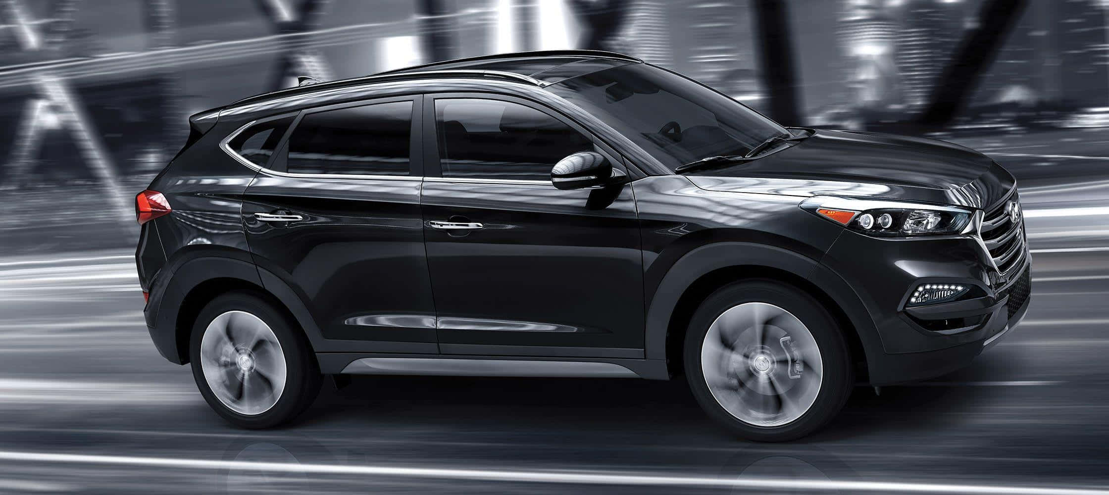 Hyundai Tucson 桌布 壁紙 — 一輛時尚的黑色SUV在模糊的城市隧道中疾馳，運動條紋強調了速度。