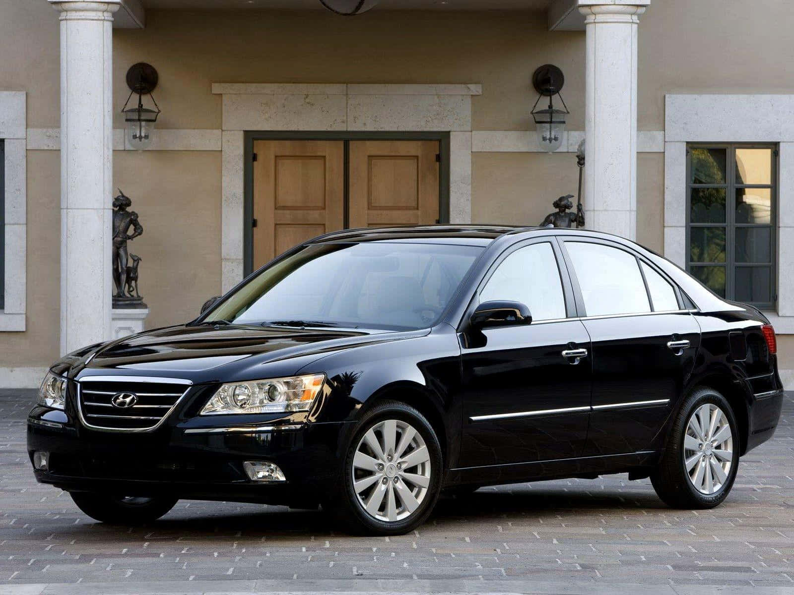 Hyundai Sonata 桌布 壁紙 — 一輛時尚的黑色現代房車在日光下閃閃發光，停在一座擁有大理石柱和雕像的宏偉豪宅前。