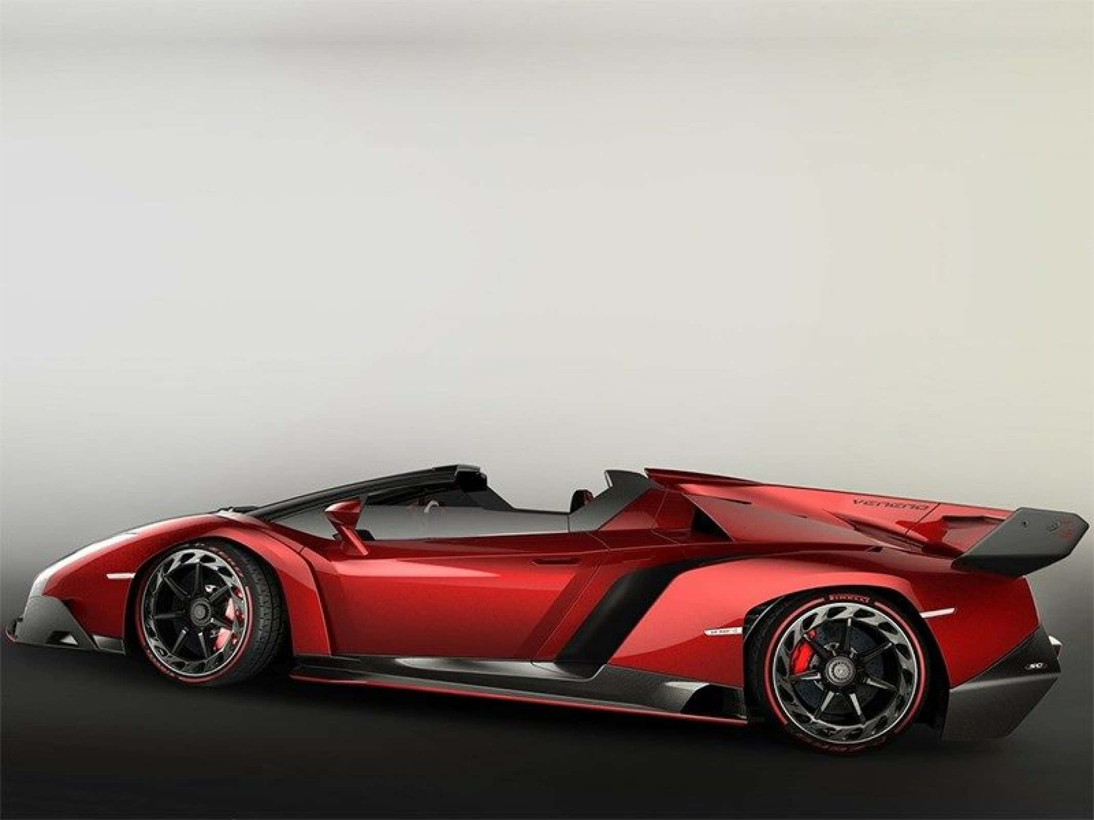 Lamborghini Veneno 桌布 壁紙 — 一輛時尚的紅色藍寶堅尼 Veneno Roadster，帶有黑色飾件和空氣動力學設計，在工作室燈光下展示。