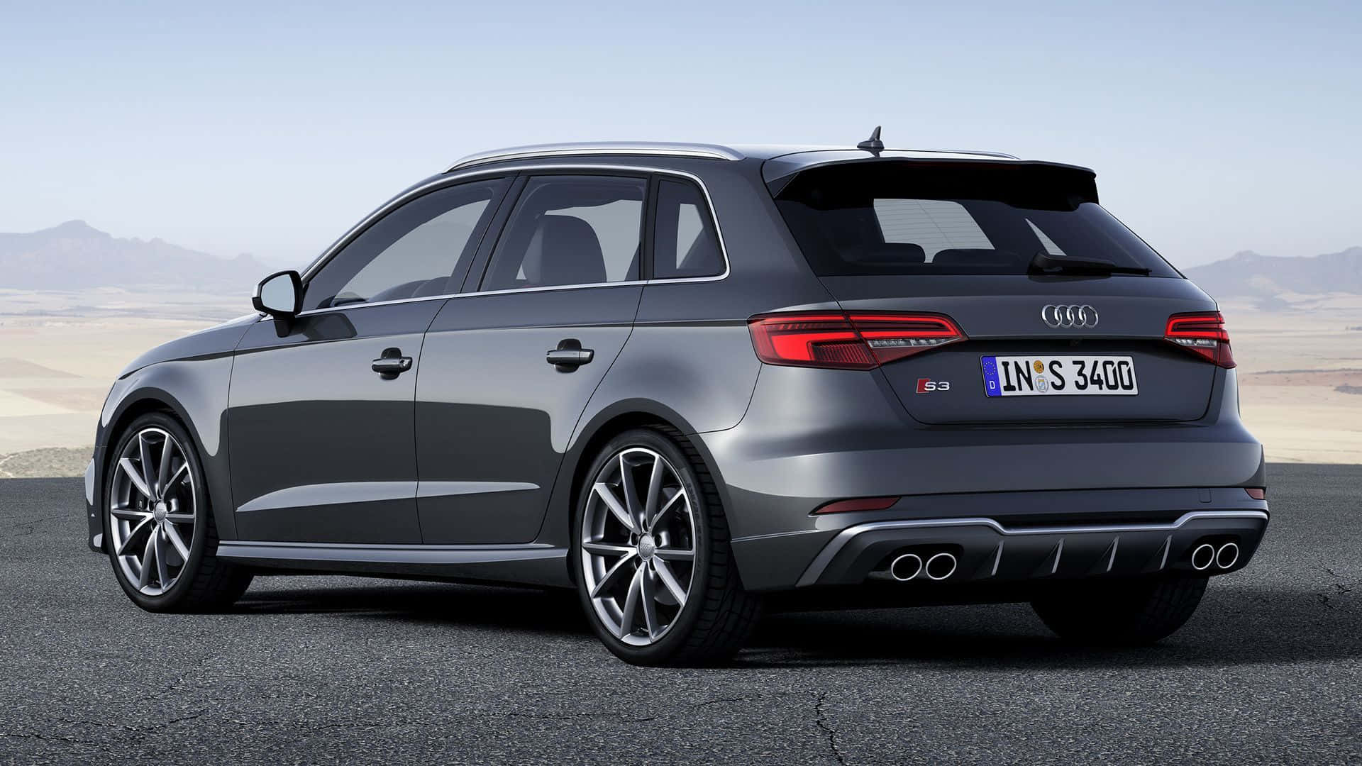 Audi S3 桌布 壁紙 — 一輛時尚的灰色奧迪S3旅行車停在瀝青路上，背景是沙漠山脈，天空晴朗。