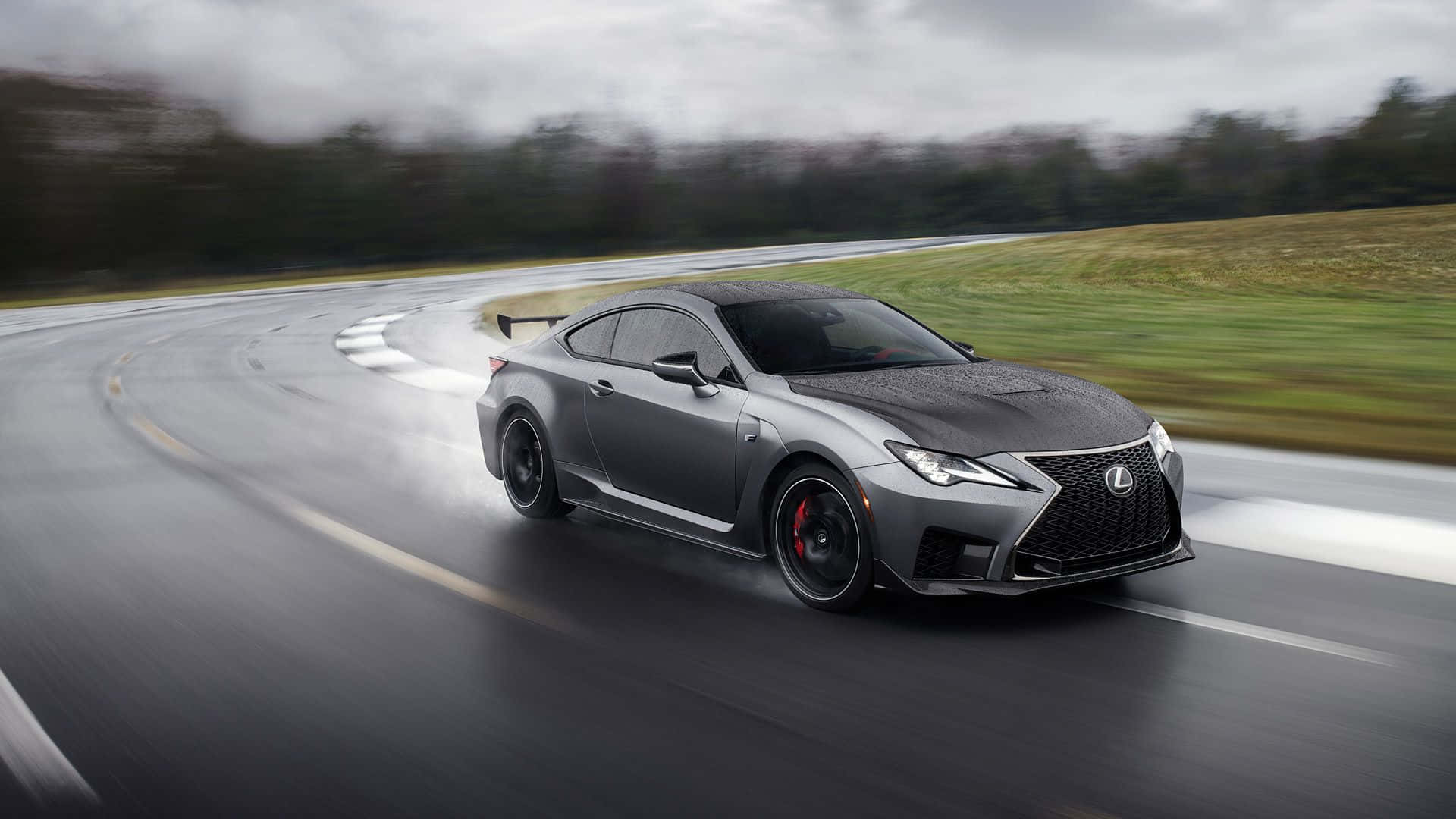 Lexus Rc F 桌布 壁紙 — 一輛時尚的灰色Lexus RC F跑車在潮濕的賽道彎道上疾馳，背景是模糊的綠植。