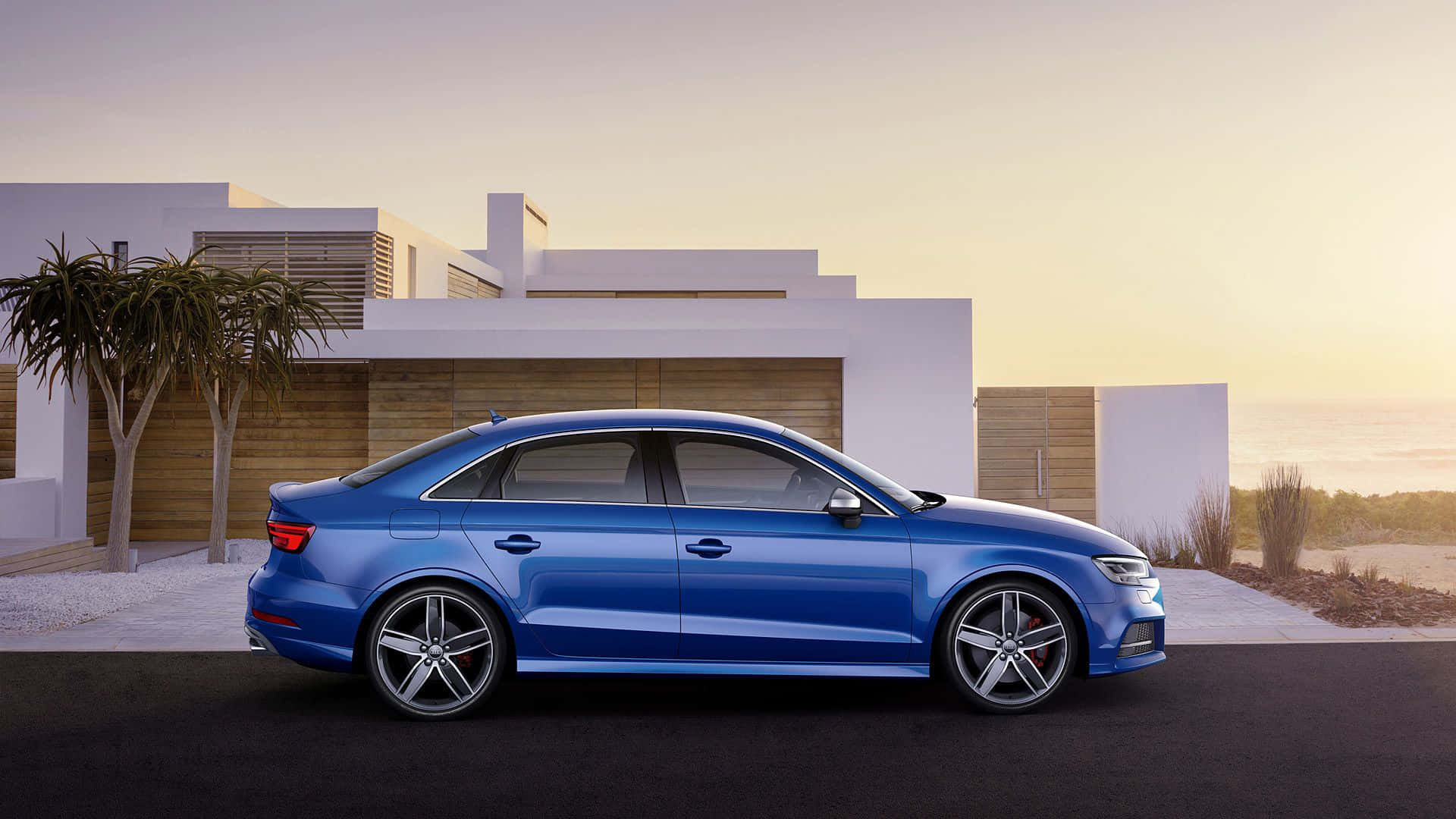 Audi S3 桌布 壁紙 — 一輛時尚的藍色轎車停在一棟現代白色房子前，夕陽西下，享有海景。