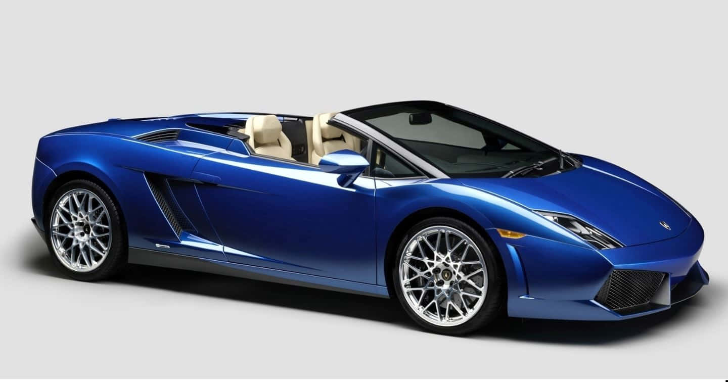 Lamborghini Gallardo 桌布 壁紙 — 一輛時尚的藍色藍寶堅尼Gallardo Spyder敞篷跑車，配備米色皮革座椅和銀色輪圈，背景為純灰色。
