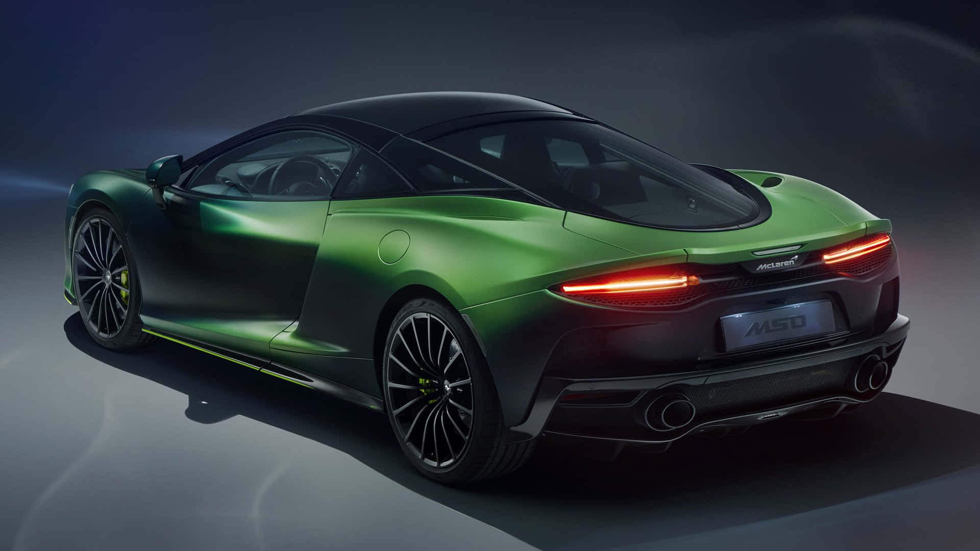 Mclaren Gt 桌布 壁紙 — 一輛時尚的綠色McLaren 450跑車在攝影棚燈光下閃耀，配備發光的尾燈和黑色飾件。