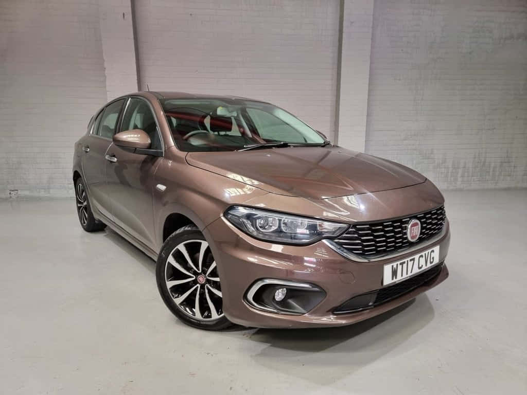 Fiat Tipo 桌布 壁紙 — 一輛時尚的青銅色菲亞特Punto停放在室內，靠著白色磚牆，配備拋光合金輪圈。