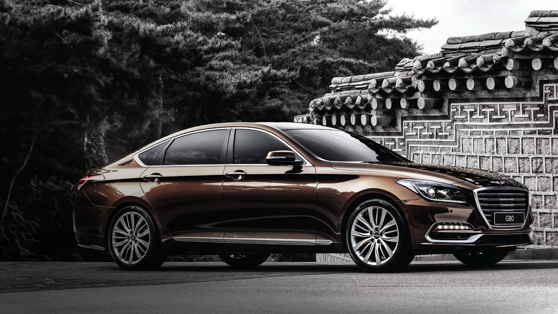 Genesis G80 桌布 壁紙 — 一輛時尚的青銅色轎車在柔和日光下，在傳統韓國瓷磚牆旁閃閃發光。