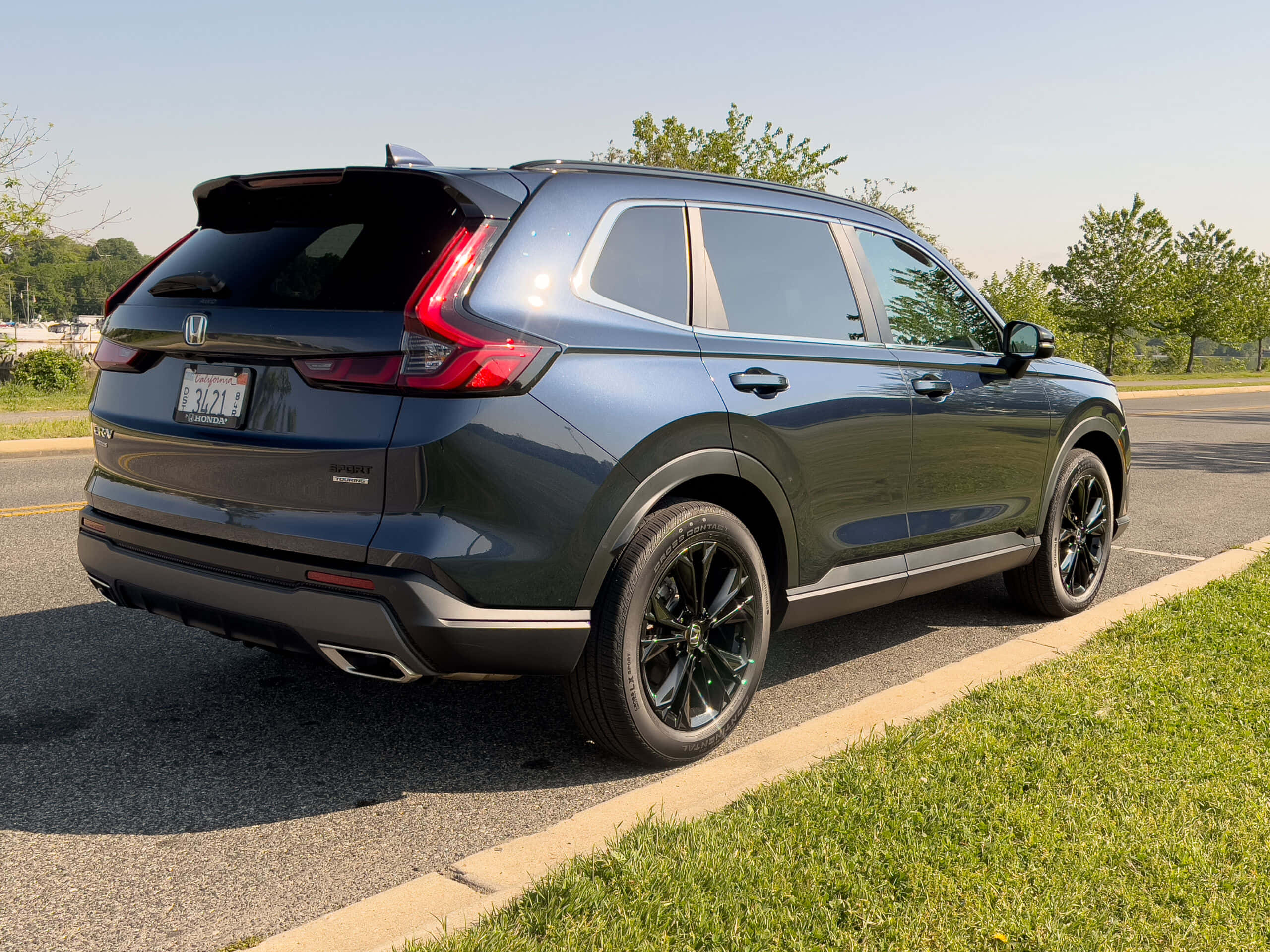 Honda Cr-v 桌布 壁紙 — 一輛時尚的深灰色本田 CR-V Sport 在陽光明媚的日子裡停在草地路邊，背景有樹木。