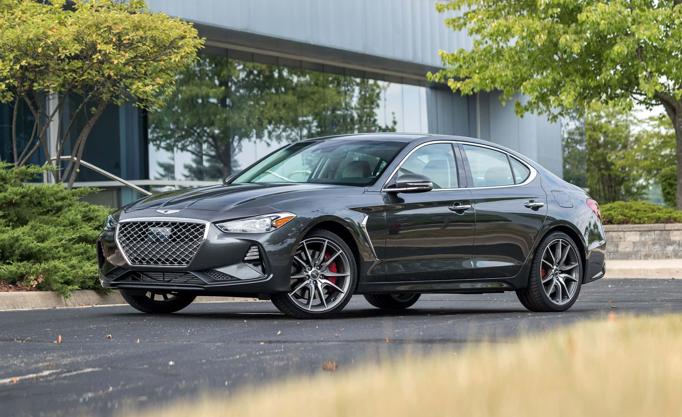 Genesis G70 桌布 壁紙 — 一輛時尚的深灰色 Genesis G70 運動轎車停放在戶外，透過合金輪圈可見紅色制動卡鉗。