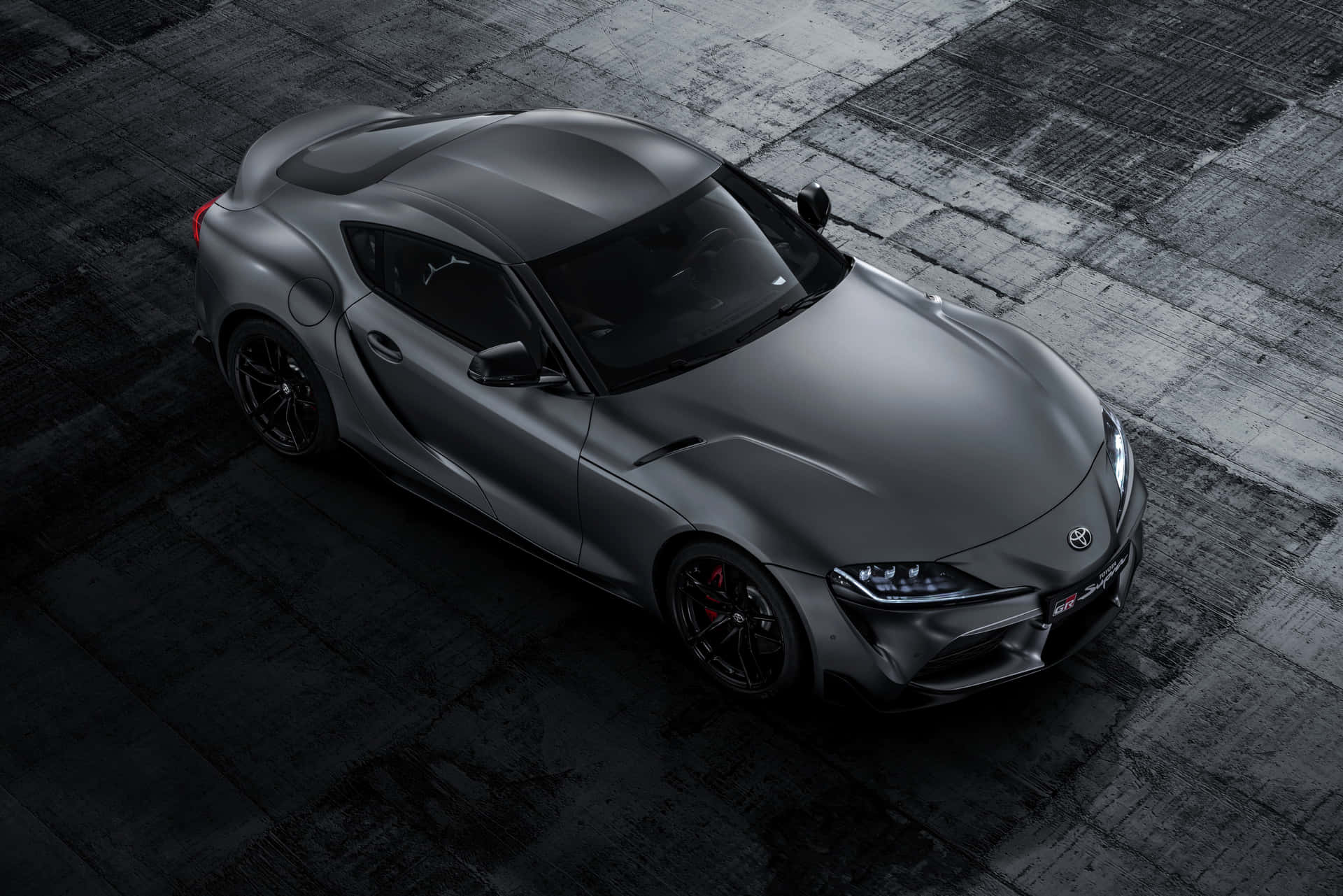 消光灰色跑車，黑色輪圈和紅色煞車卡鉗，在深色混凝土上。 — Toyota Supra 壁紙