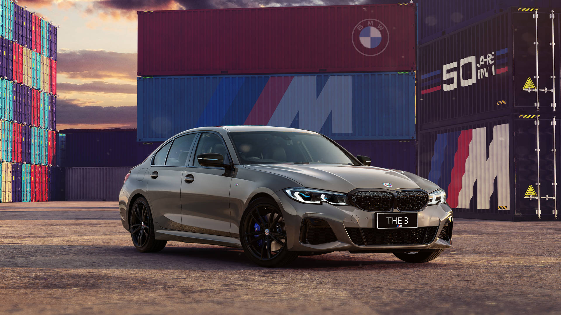 銀色BMW M3轎車停放在色彩繽紛的貨櫃之間。 — 4K 壁紙