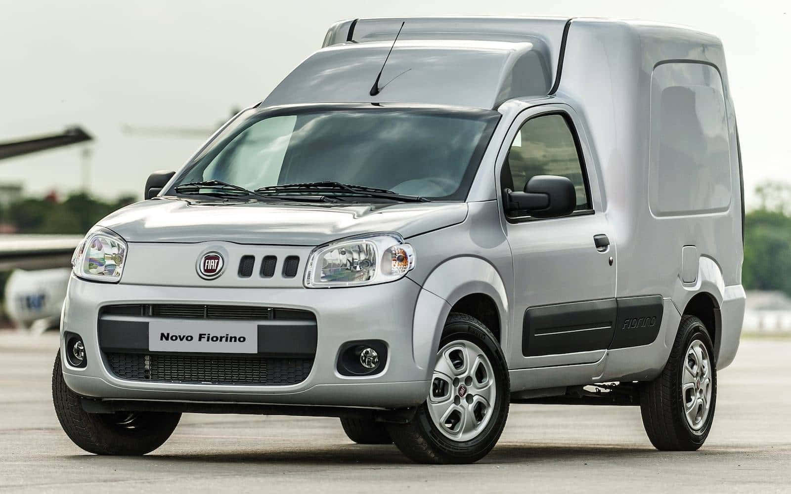 Fiat Fiorino 桌布 壁紙 — 一輛時尚的銀色 Fiat Novo Fiorino 廂型車停放在露天鋪砌場地上，天空多雲。
