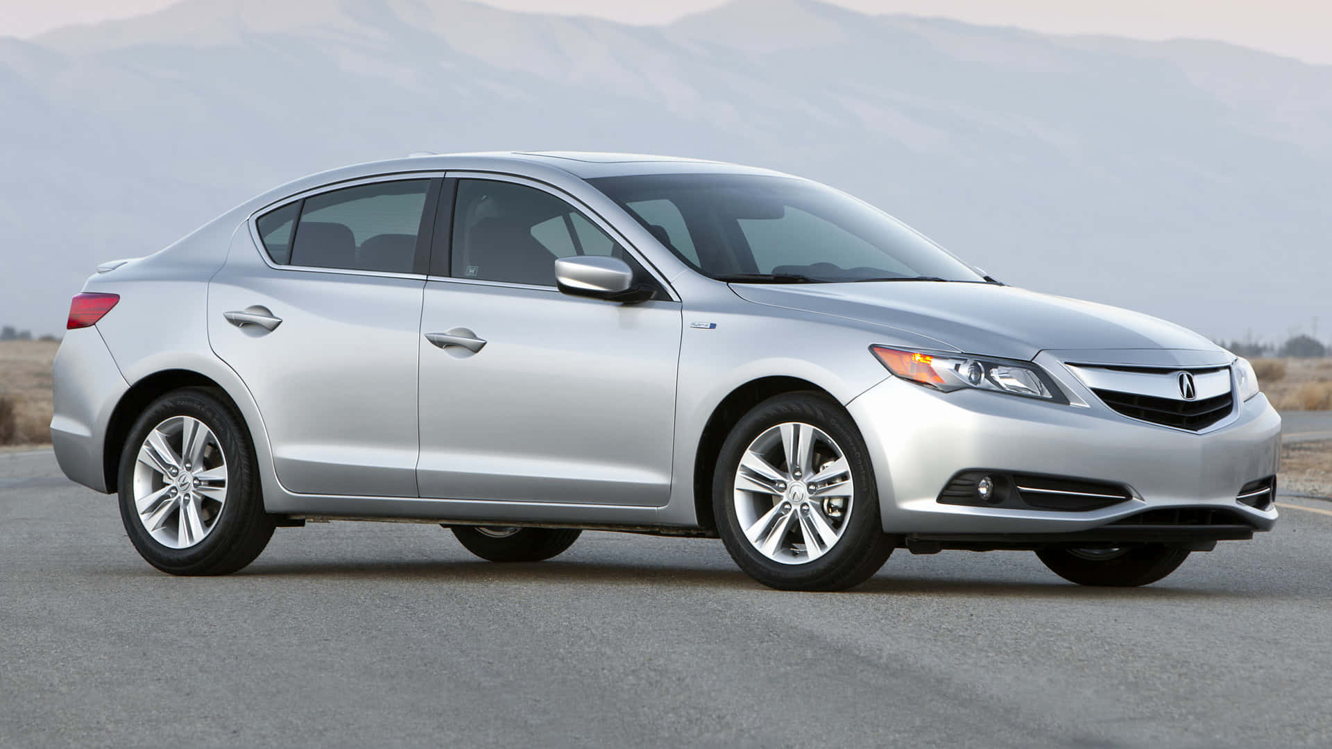 Acura Ilx 桌布 壁紙 — 一輛時尚的銀色轎車停在柏油路上，背景是朦朧的山巒。